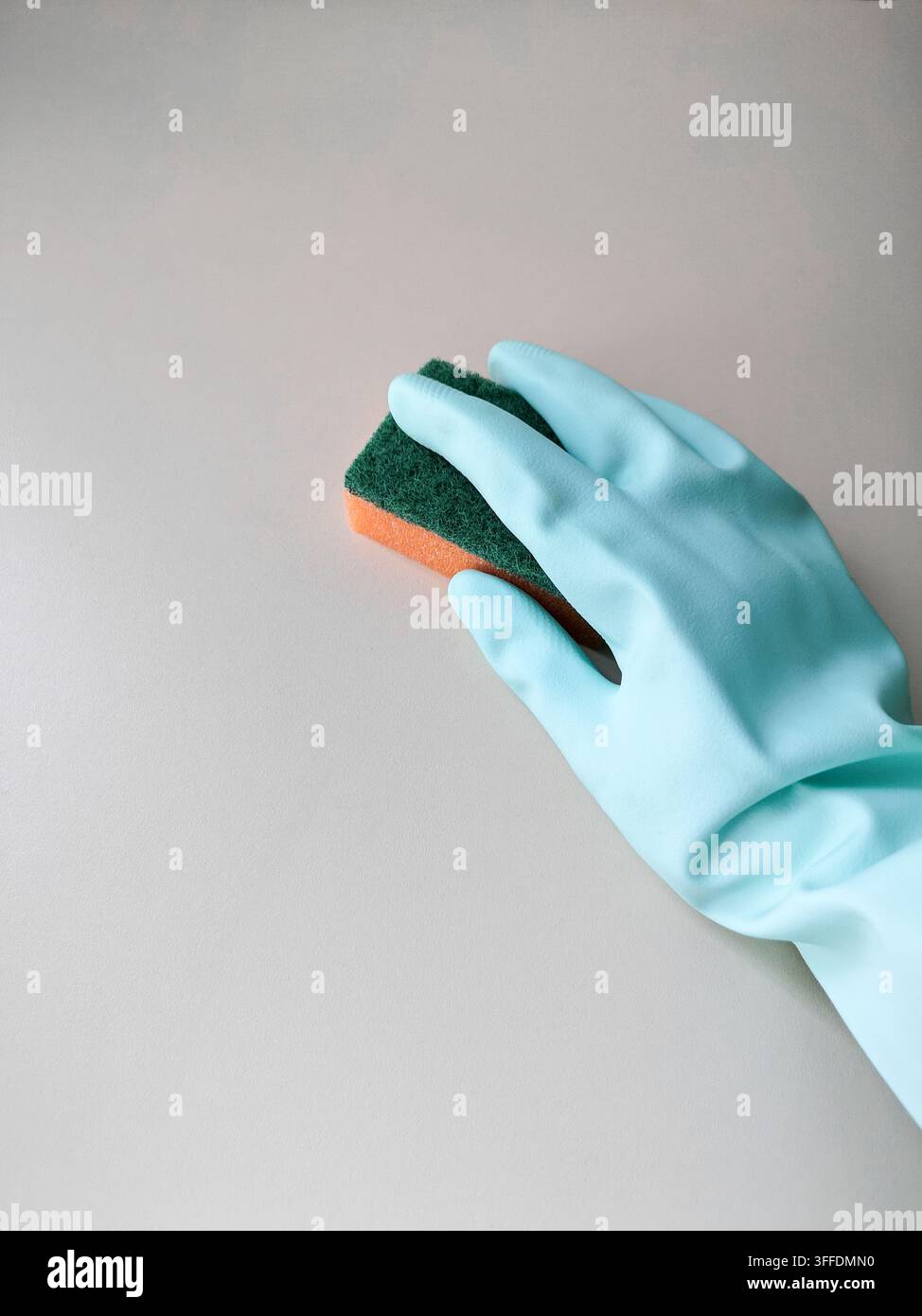 Pulizia e disinfezione. Una donna in un guanto blu tiene una spugna arancione e lava una parete di luce. Foto Stock