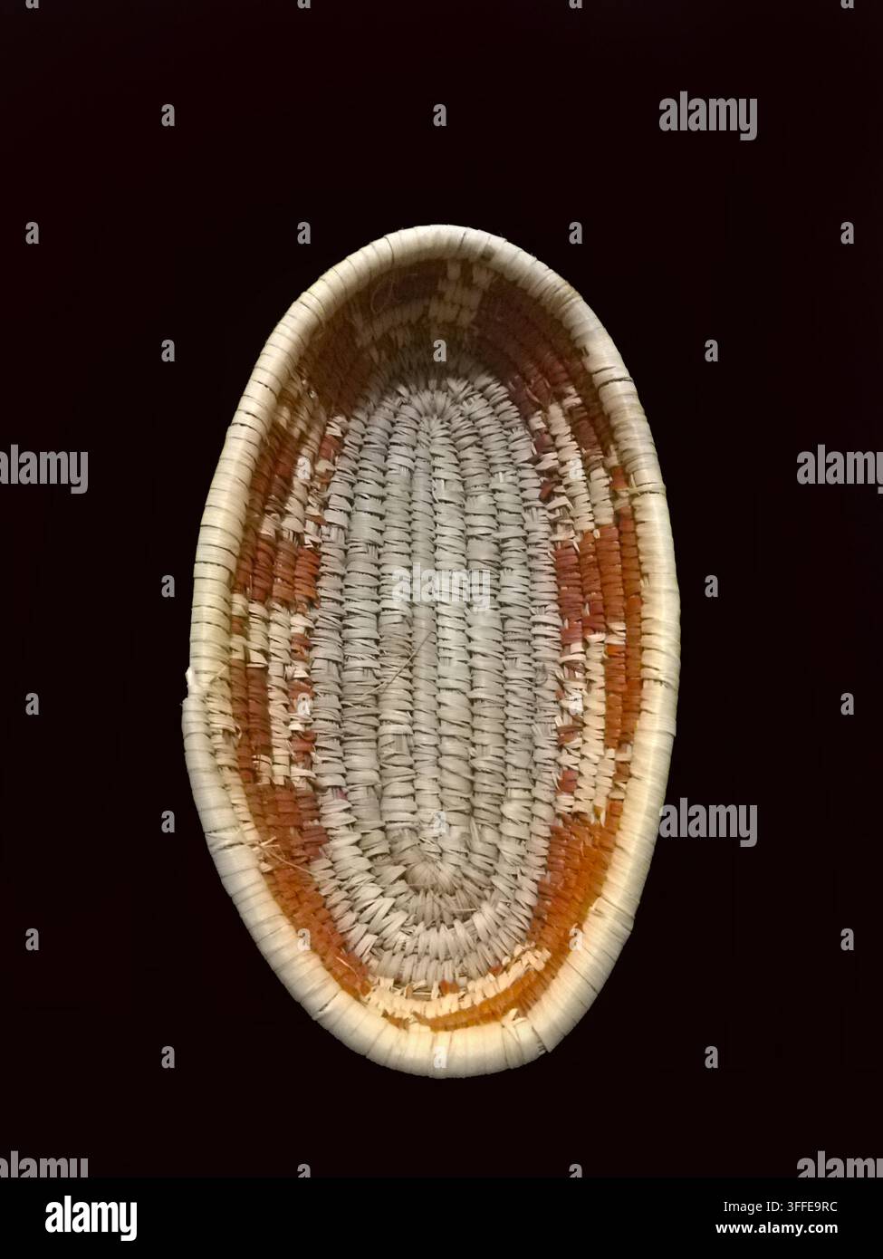 Vista di un cesto da parete avvolto fatto a mano con un sorprendente motivo geometrico a forma di stella centrato all'interno di una larga fascia arancione ruggine, Multan, Punjab, Pakistan Foto Stock