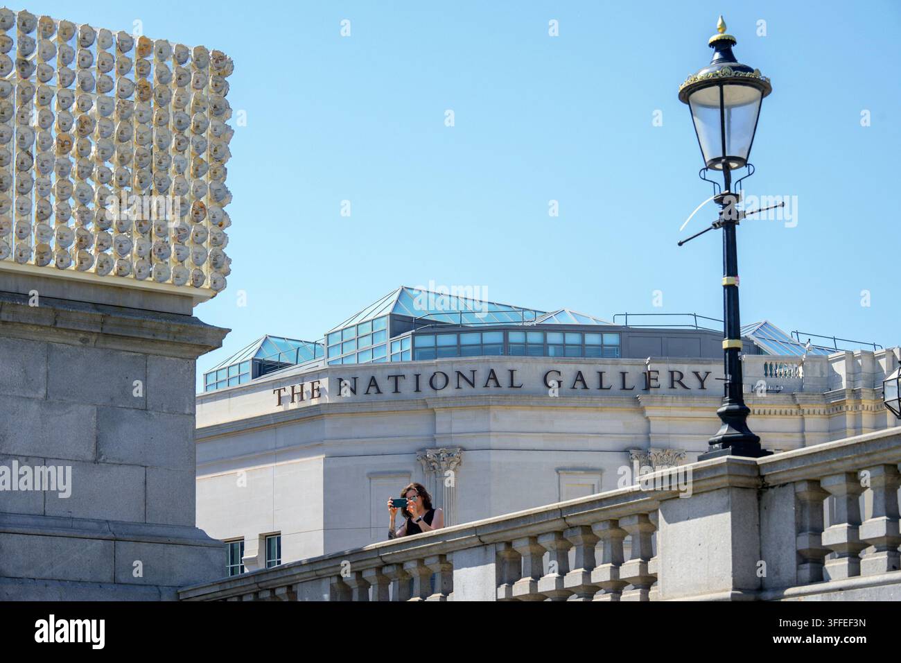 Londra, Regno Unito. Trafalgar Square – Turista che scatta una foto davanti all’ala Sainsbury della National Gallery Foto Stock