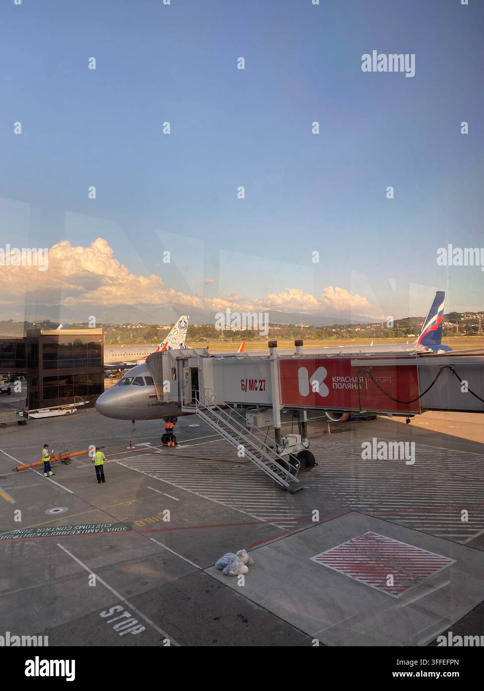 Sochi, Russia – 6 settembre 2022: Aereo passeggeri e personale di terra si preparano accanto al ponte di imbarco dell’aeroporto. - Immagine stock catturata con smartphone