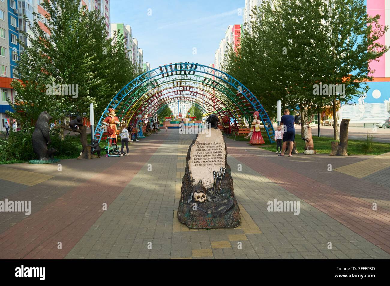 Tiumen, Russia - 6 settembre 2026: Viale pedonale decorativo nel distretto di Novopatrushevo con segnacolo in pietra, archi arcobaleno, sculture di personaggi, un Foto Stock