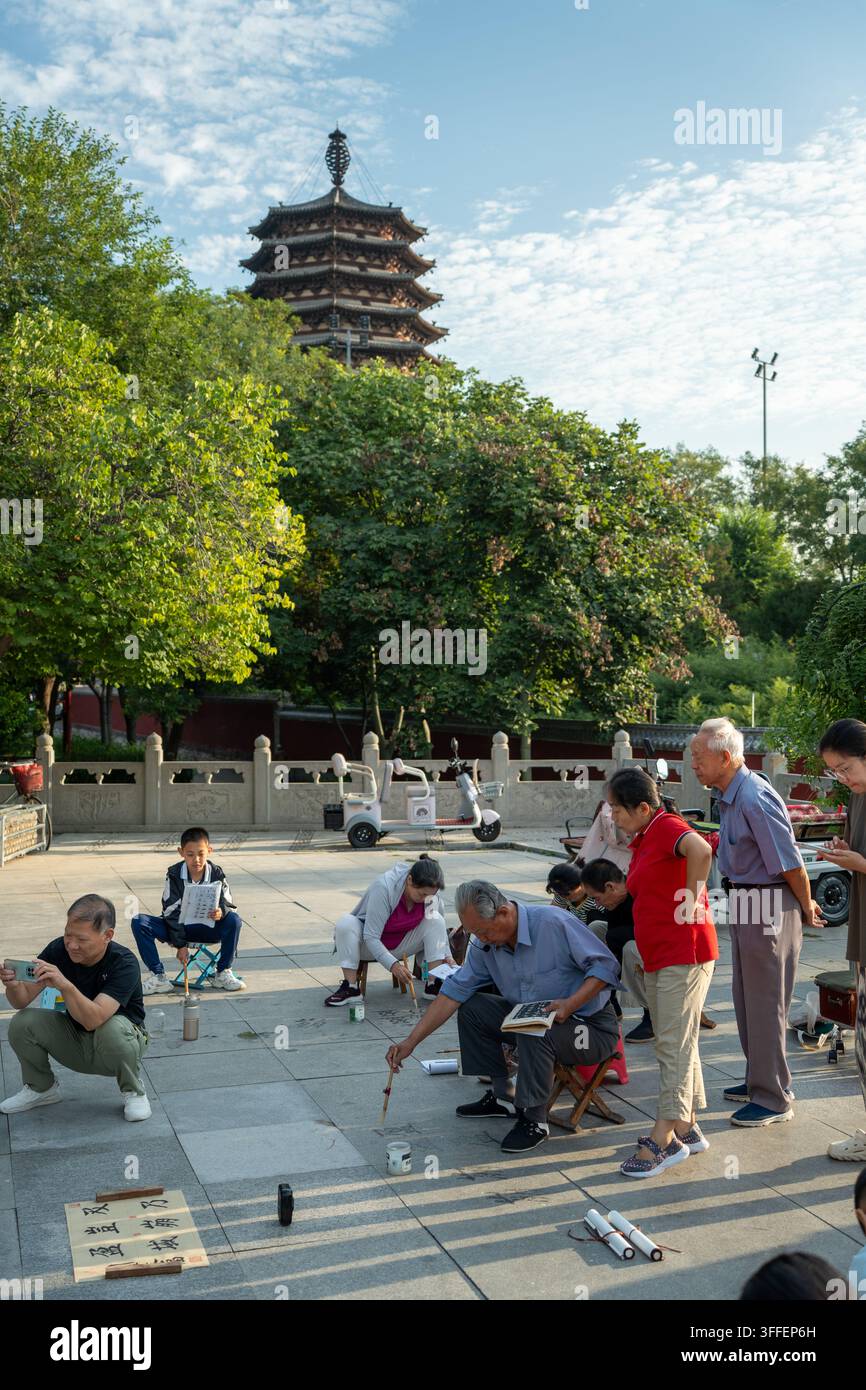 Residenti che praticano la calligrafia con il pennello cinese davanti alla pagoda Lingxiao a Zhengding, Cina Foto Stock