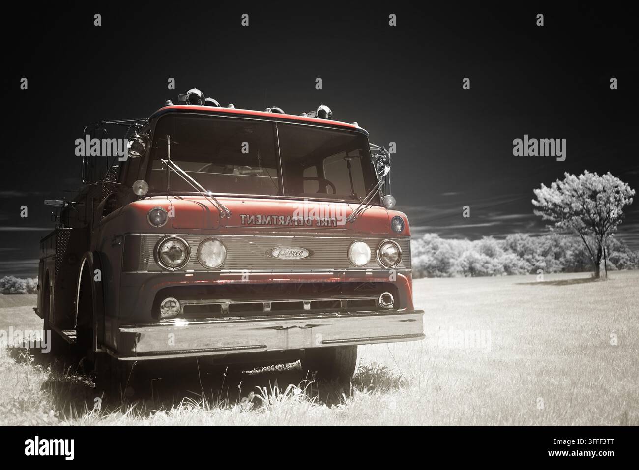 Immagine a infrarossi a falsi colori di un vecchio camion dei pompieri rosso abbandonato in un pascolo. Riflessi brillanti e luminosi con un cielo quasi senza nuvole Foto Stock