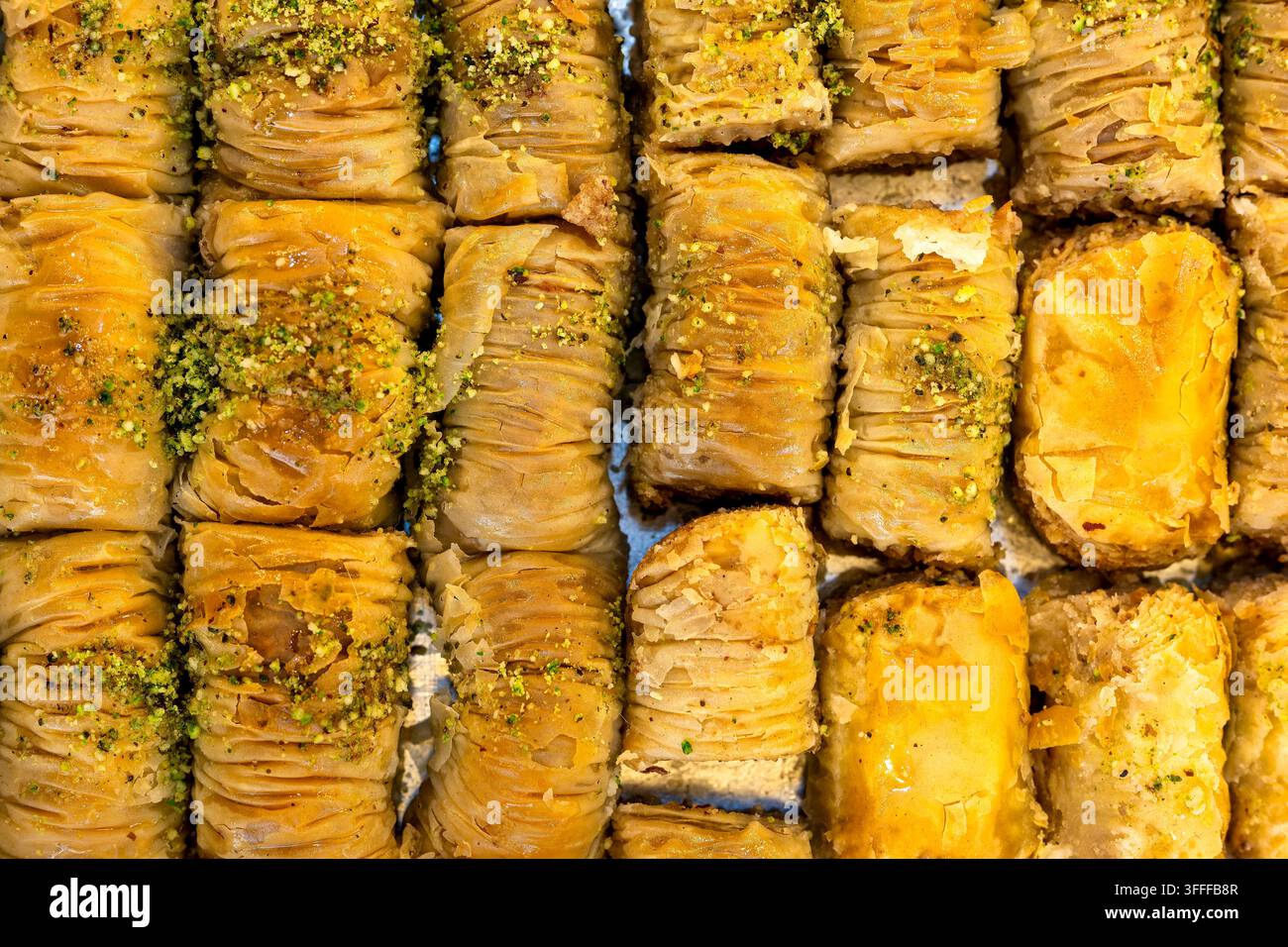 Dessert turco tradizionale arrotolato con strati di sfoglia e guarnizione di pistacchi spezzati. Foto Stock
