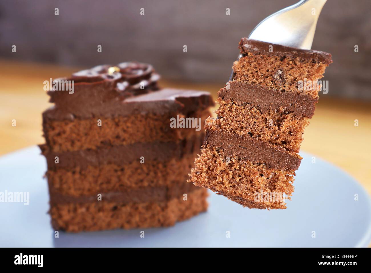 Prima piano di una forchetta che solleva una deliziosa fetta di ricco dolce al cioccolato fondente a strati Foto Stock