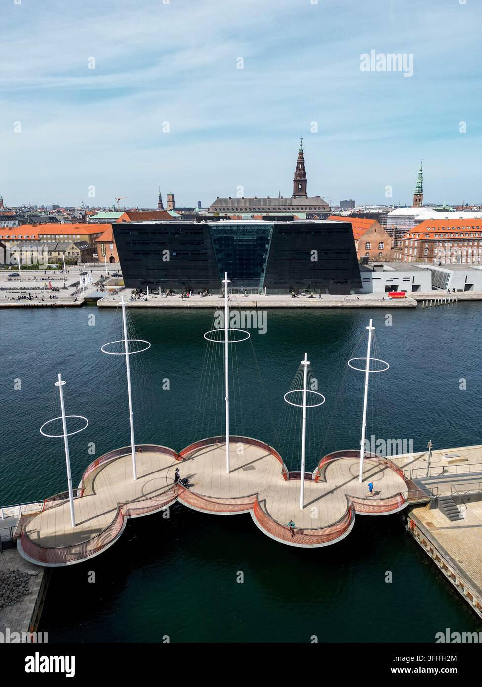Vista aerea del ponte Cirkelbroen con piattaforme circolari e pali sopra l'acqua, con la Black Diamond Royal Library e l'architettura storica della città Foto Stock