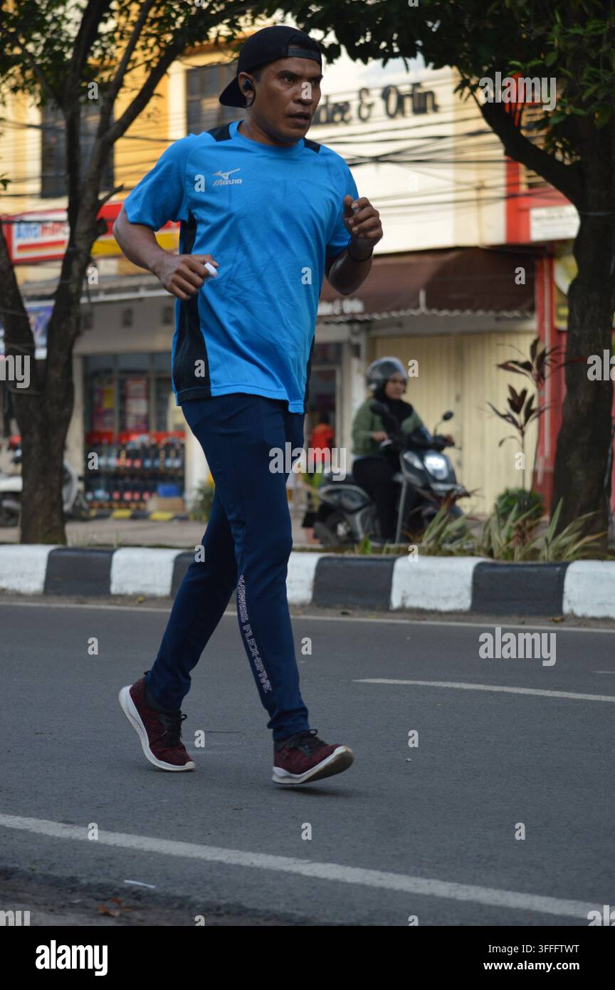 Uomo asiatico adulto attivo che fa jogging su una strada cittadina durante l'allenamento mattutino Foto Stock