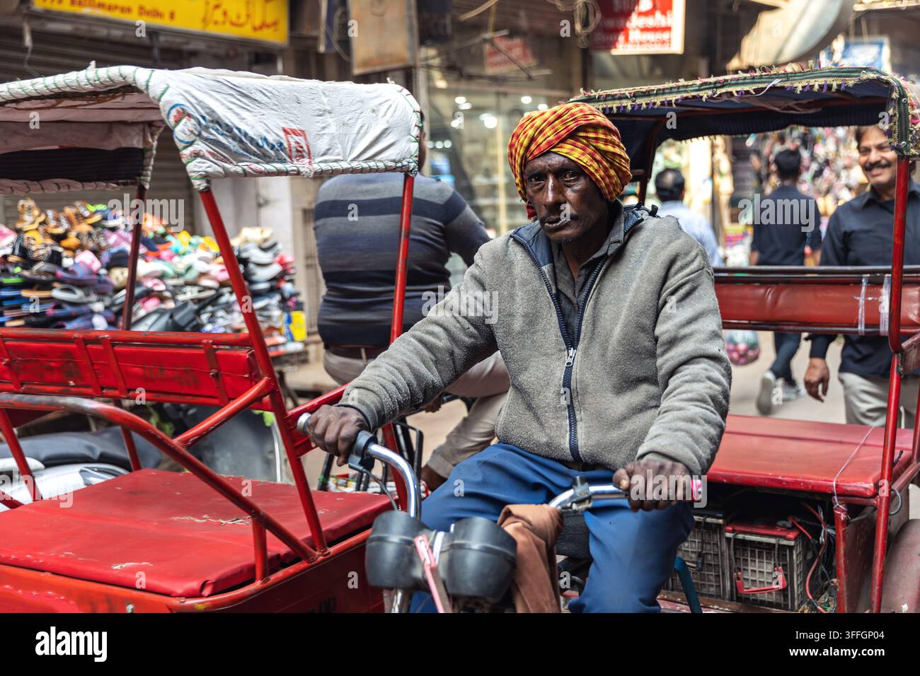 Autista di rickshaw a pedalata in piedi accanto a rickshaw su una strada a New Delhi, India. Foto Stock