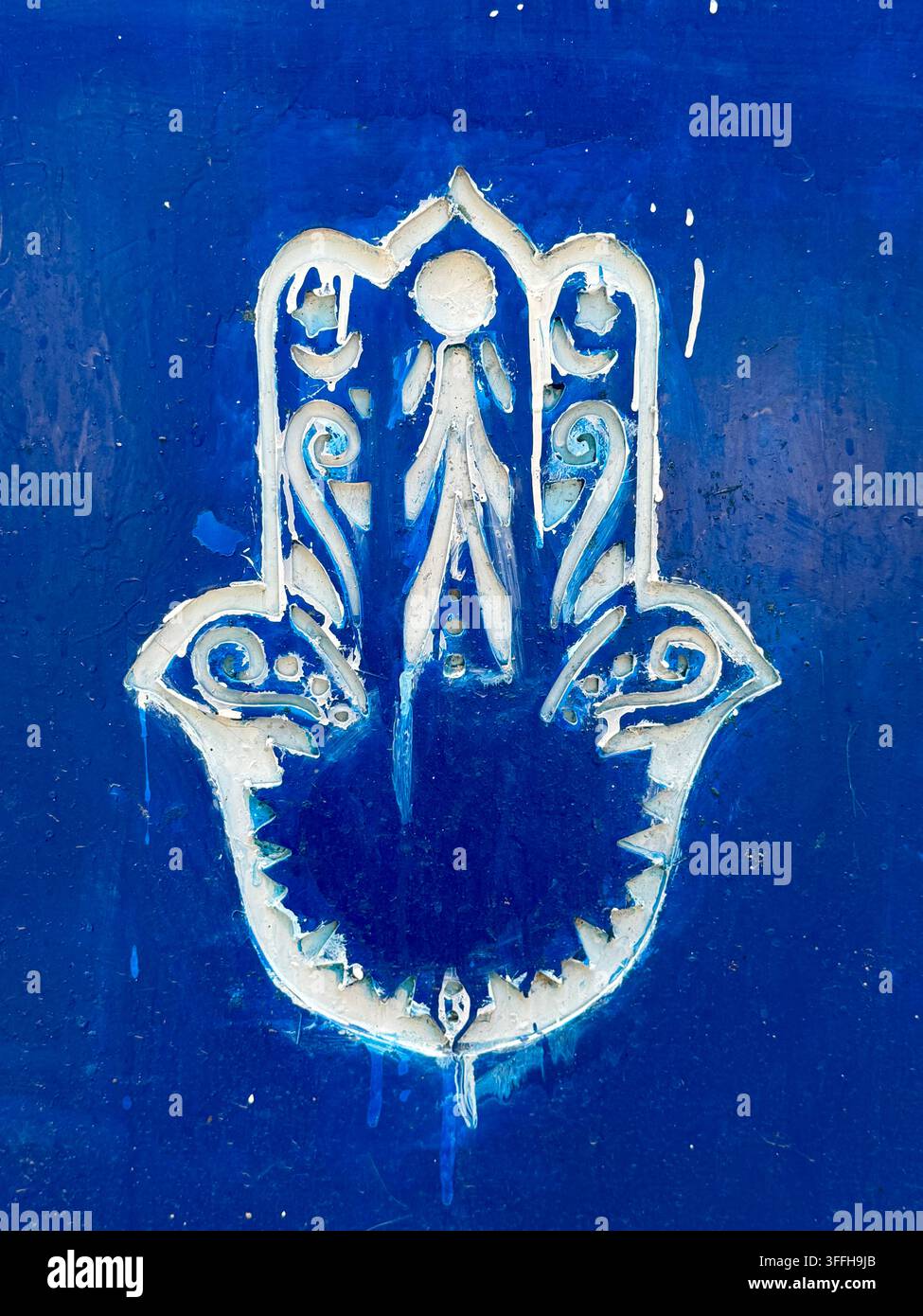 Khomsa o Mano di Fatima dipinta, un simbolo tradizionale di protezione della hamsa, su una superficie blu vivace a Tunisi, Tunisia - Immagine stock catturata con smartphone
