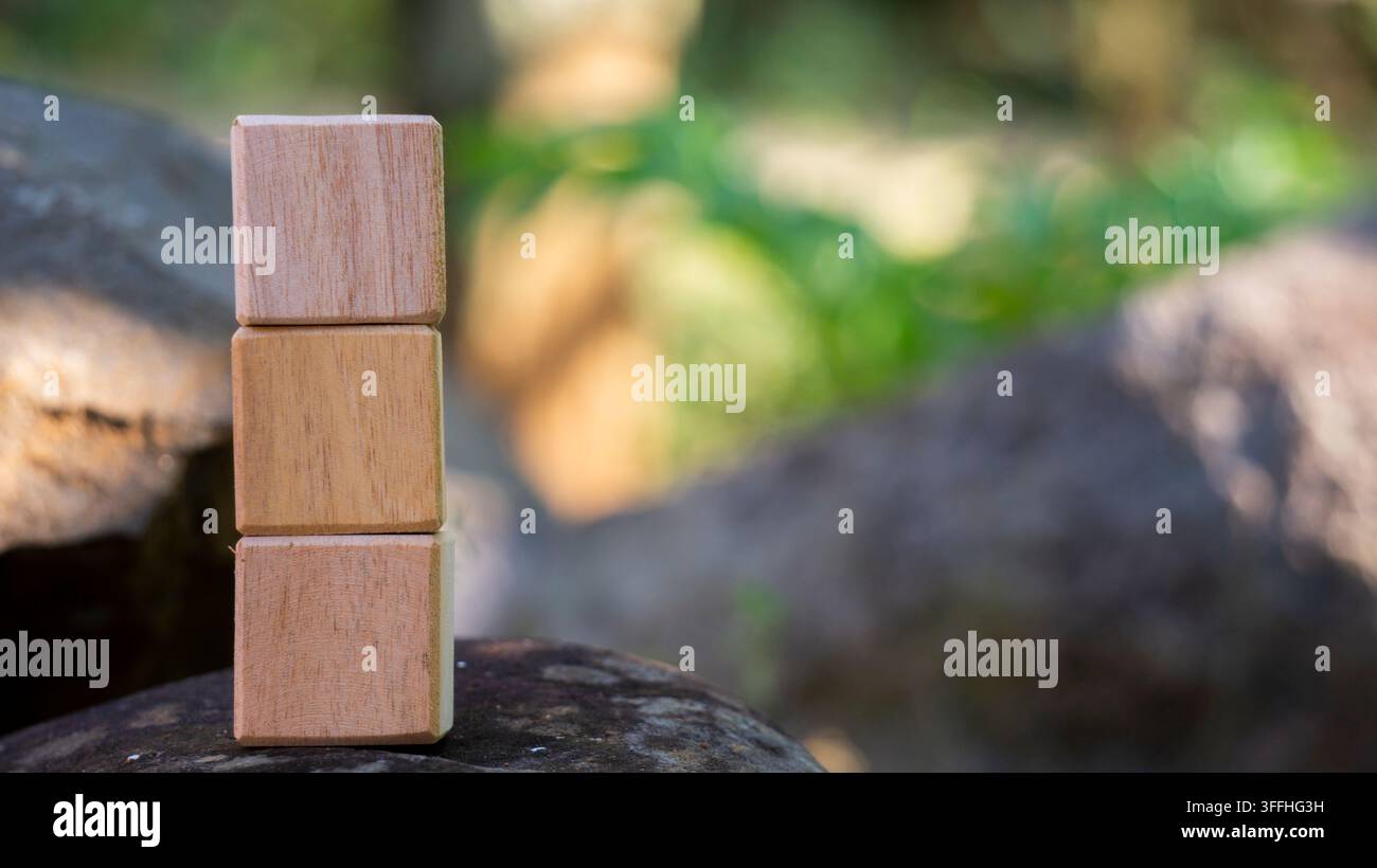 Tre blocchi di legno impilati su roccia sfondo naturale all'aperto Foto Stock