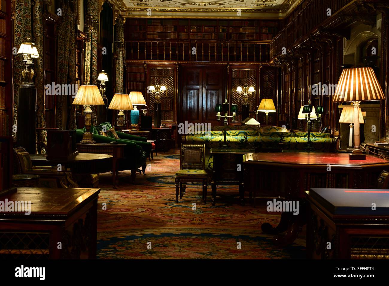 Interno della biblioteca di Chatsworth House con scaffali in legno, lampade da tavolo e arredamento classico Foto Stock