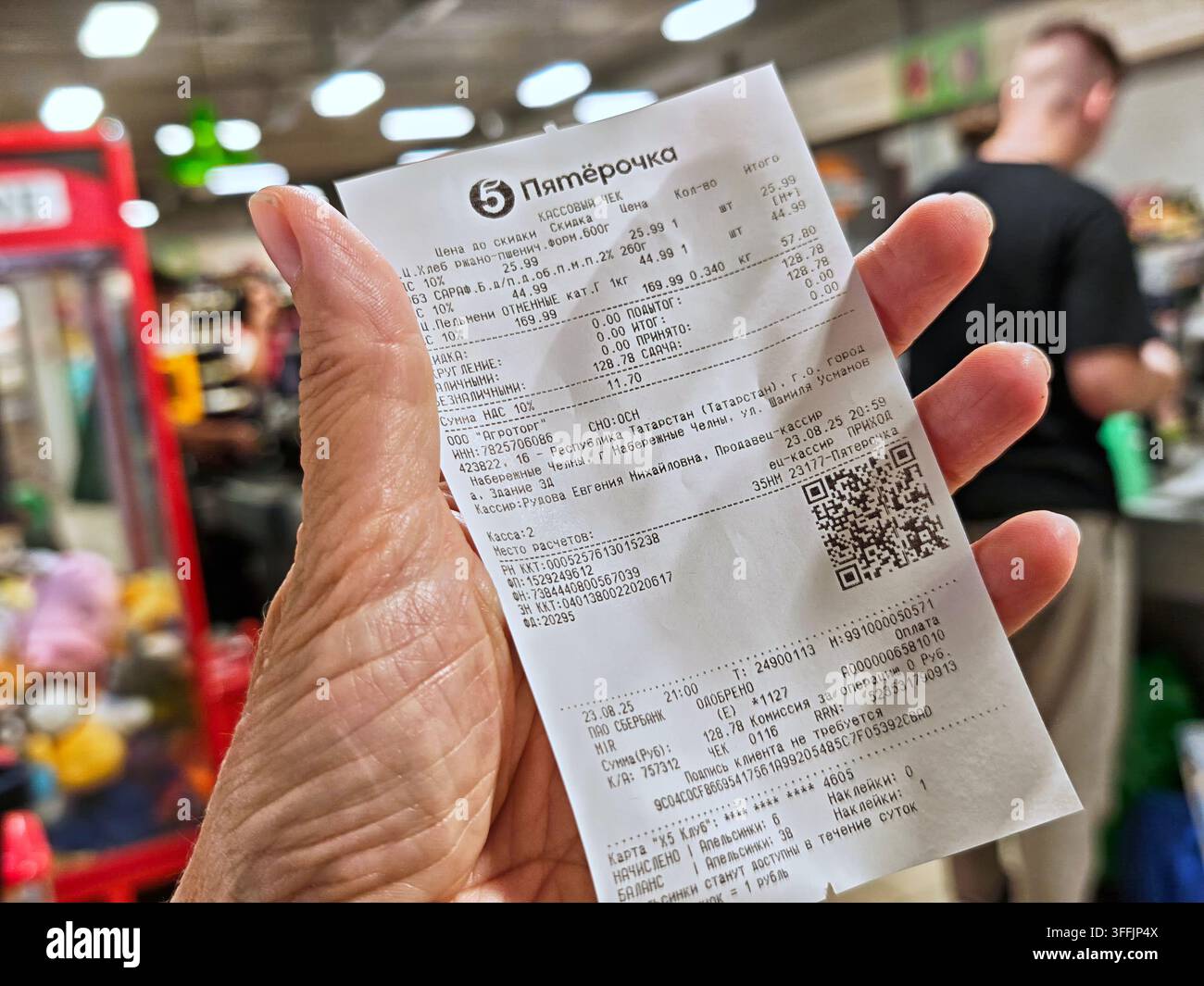 Naberezhnye Chelny, Russia – 23 agosto 2025: Una persona tiene un scontrino della spesa in mano dopo aver pagato gli articoli in un supermercato. Lo shopping ha preso Foto Stock