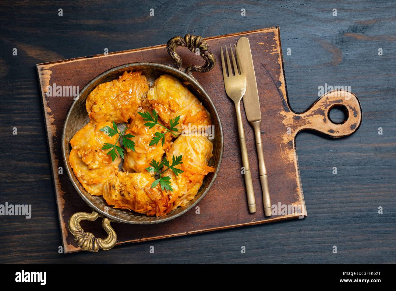 Vista dall'alto di involtini di cavolo fatti in casa in padella tradizionale. Flat lay di involtini di cavolo ripieni o golubtsi con salsa di pomodoro e guarnizione di carote in stile rustico Foto Stock
