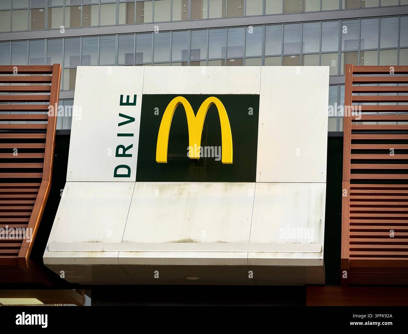 Foto ravvicinata di un pannello McDrive di McDonald's con archi dorati su una moderna facciata in doghe di legno a Vilnius, Lituania. Foto Stock