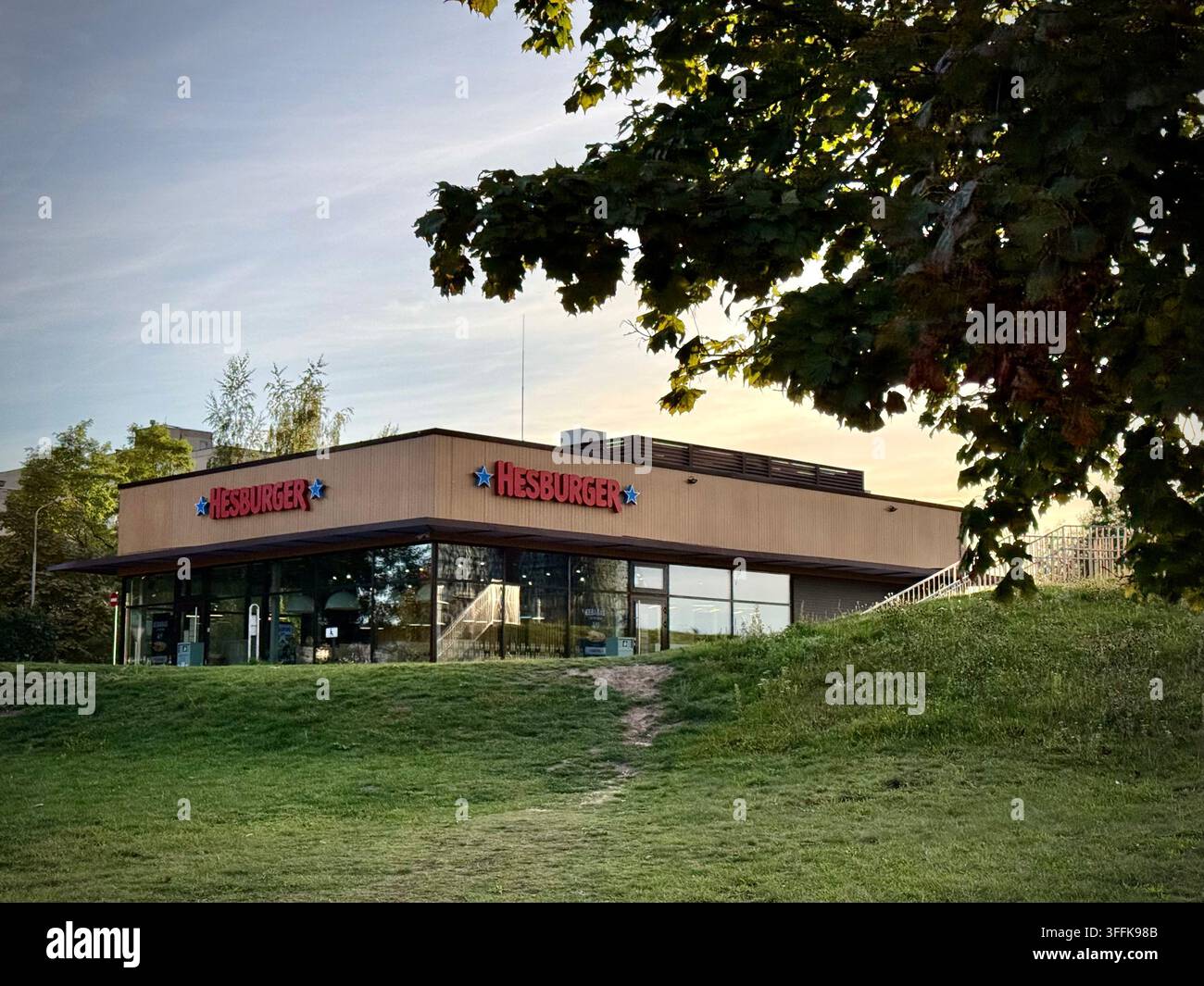 Foto ampia di un padiglione moderno di ristorante fast food Hesburger su un pendio erboso a Vilnius, Lituania. - Immagine stock catturata con smartphone