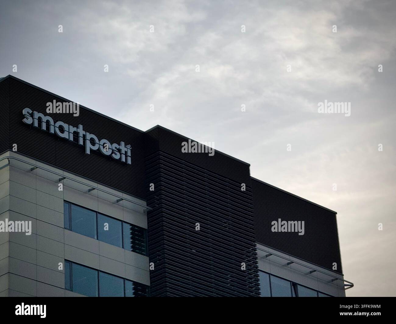 Foto ad angolazione bassa del logo aziendale Smartposti su una facciata di edificio moderno a uffici a Vilnius, Lituania. - Immagine stock catturata con smartphone