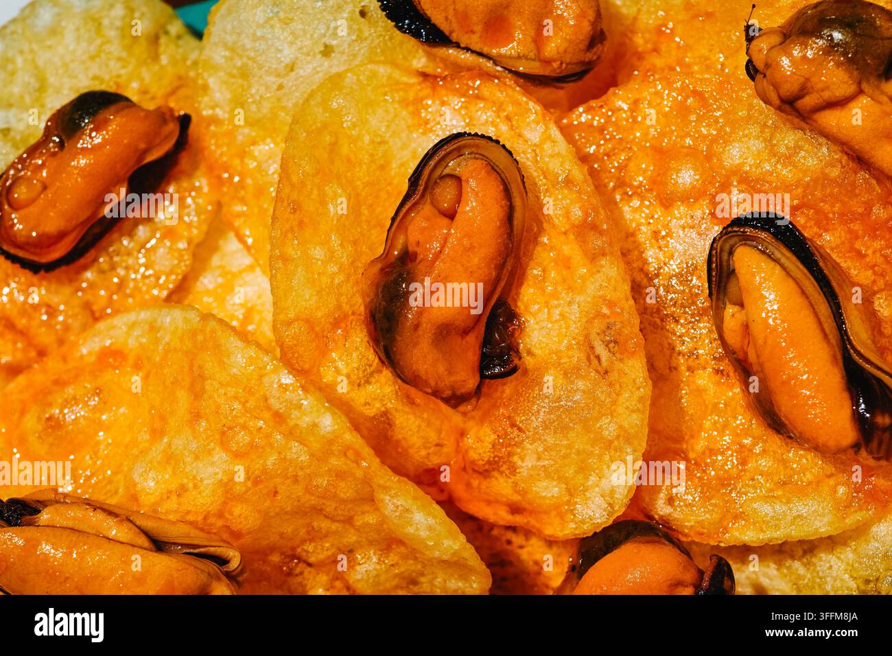Strati di patatine fritte croccanti ricoperte di salsa escabeche e cosparse di cozze creano un primo piano riccamente strutturato di un bar tradizionale spagnolo o Foto Stock