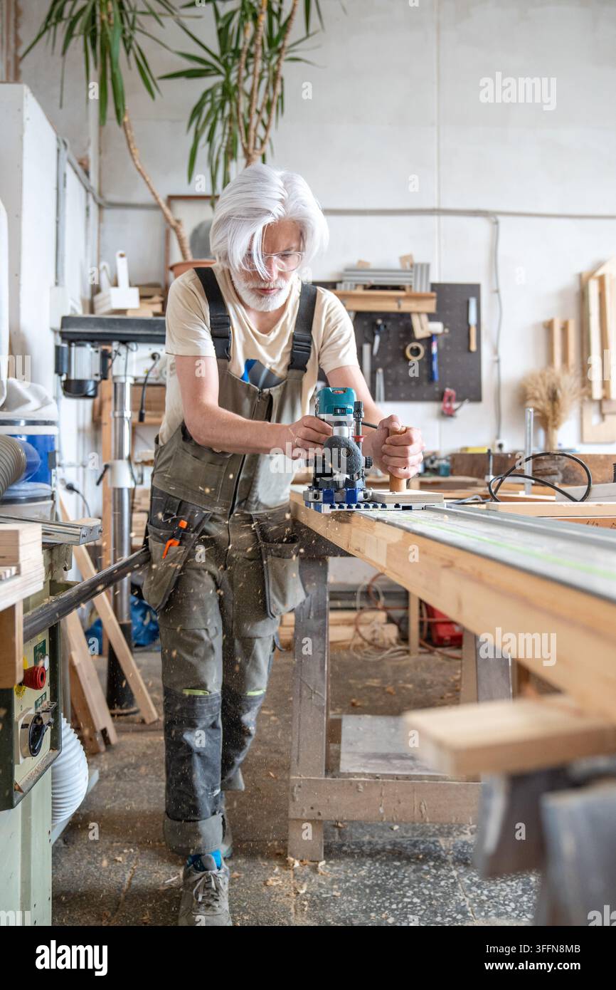 Lavoro di una fresatrice elettrica per legno con guida a binario in un laboratorio di restauro per la riparazione di porte antiche Foto Stock