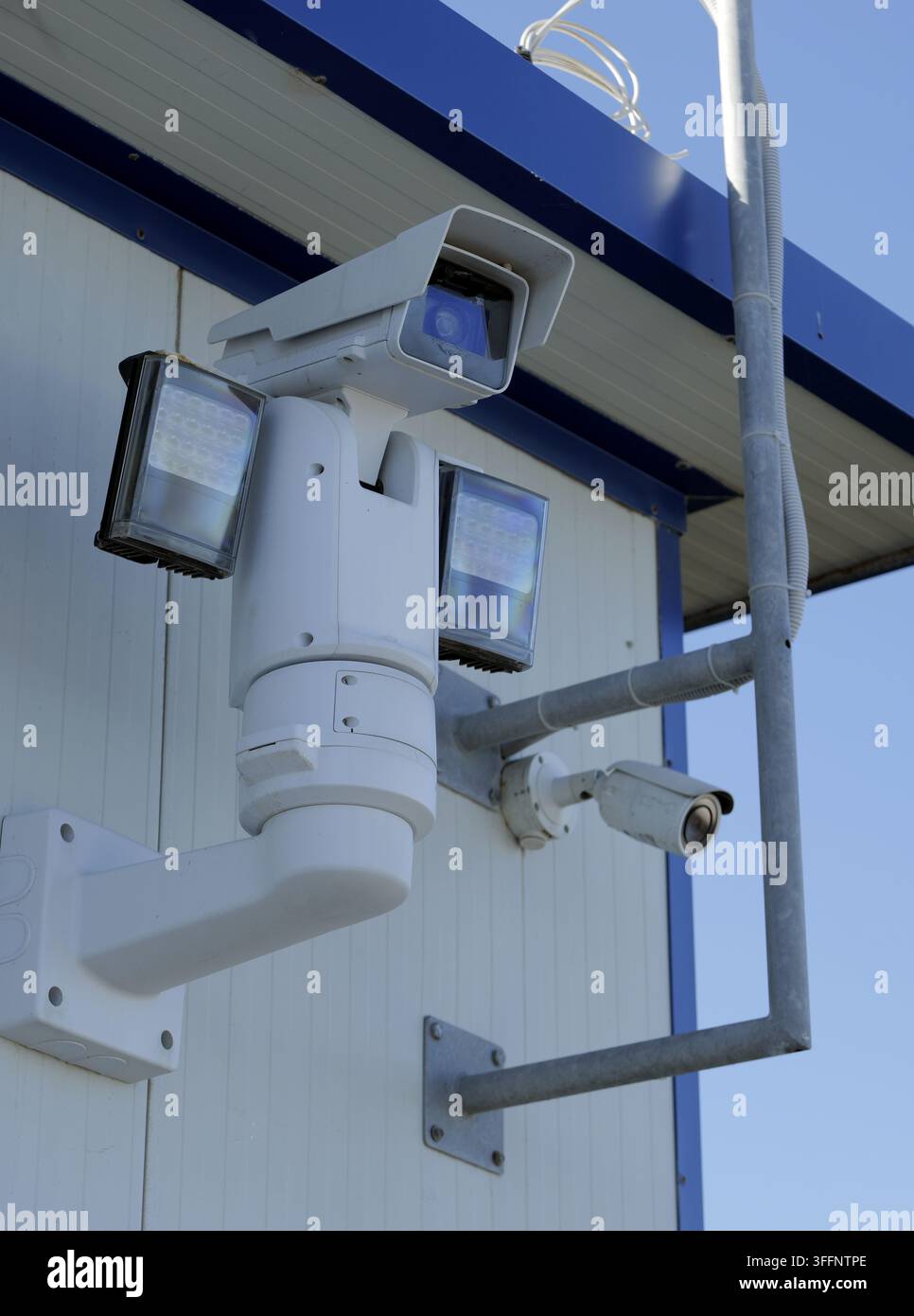 Configurazione di sorveglianza moderna con una telecamera PTZ rotante con fari LED e una telecamera a cupola fissa montata sull'esterno di un edificio. Fornisce una copertura completa Foto Stock