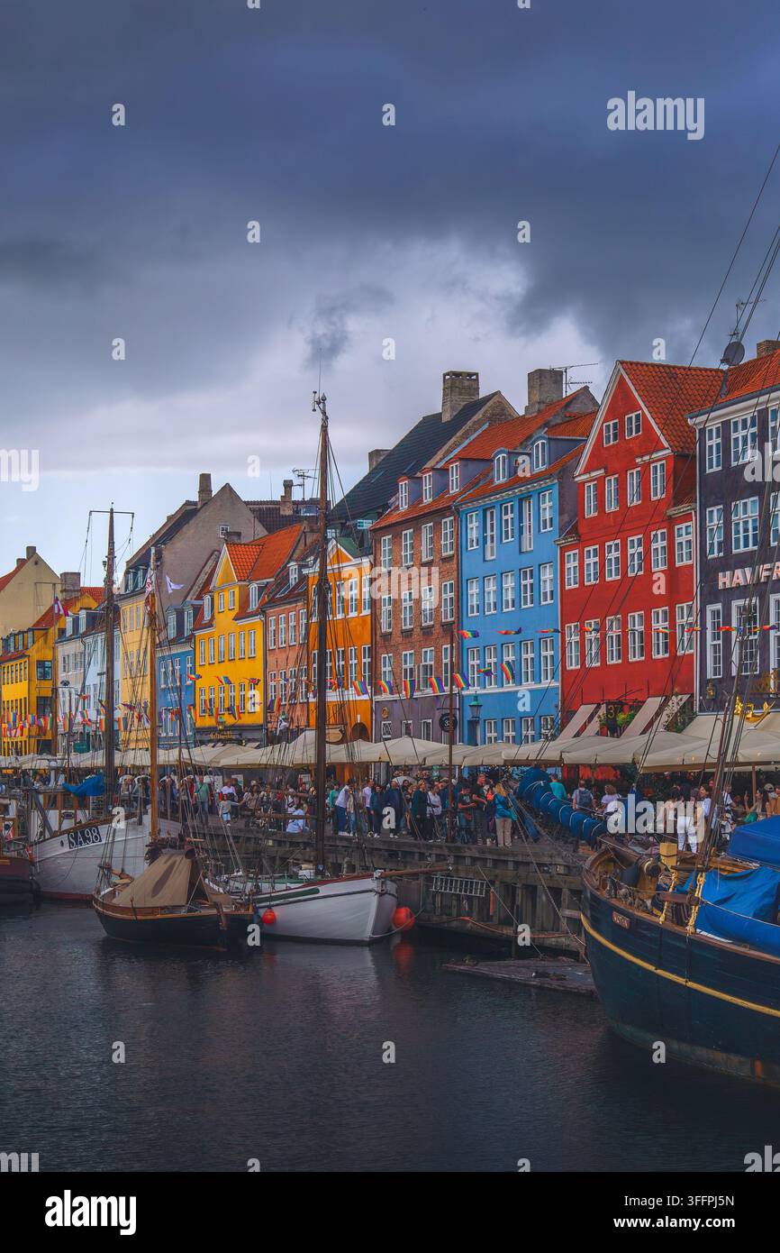 Canale Nyhavn a Copenaghen, Danimarca, fiancheggiato da case storiche colorate e barche ormeggiate sotto drammatiche nuvole di tempesta Foto Stock