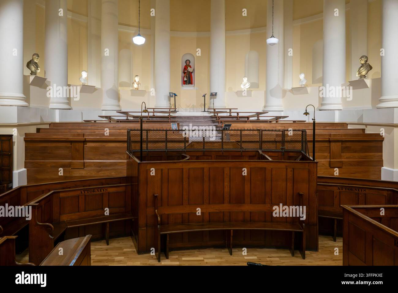 Un'aula di tribunale tradizionale e vuota con posti a sedere in legno a gradini, ringhiere ornate e colonne classiche imponenti sotto un soffitto a cupola Foto Stock