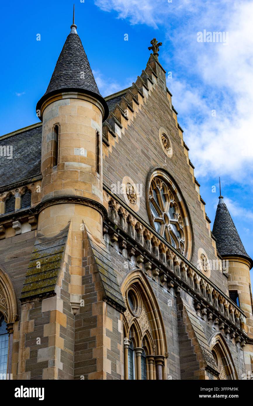 Una vista dettagliata di un edificio storico in stile gotico con intricate sculture in pietra e archi a sesto acuto sotto un cielo blu a Dundee, Scozia, Regno Unito. Foto Stock