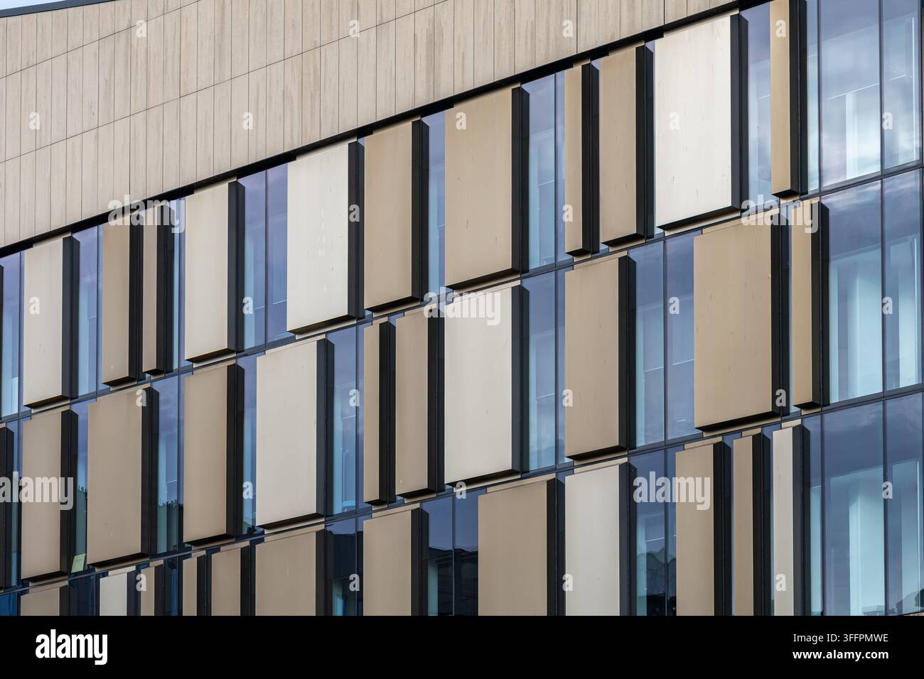 Un primo piano di una facciata di edificio contemporaneo con un motivo geometrico di finestre e pannelli in toni neutri a Glasgow, Scozia, Regno Unito. Foto Stock