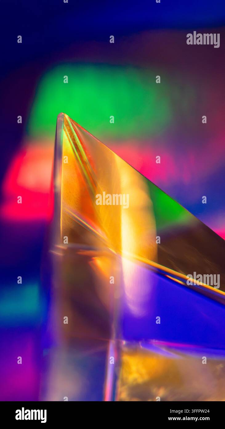 Primo piano di un prisma di vetro iridescente che riflette vividi colori neon su uno sfondo futuristico scuro, creando una composizione ottica astratta con Foto Stock