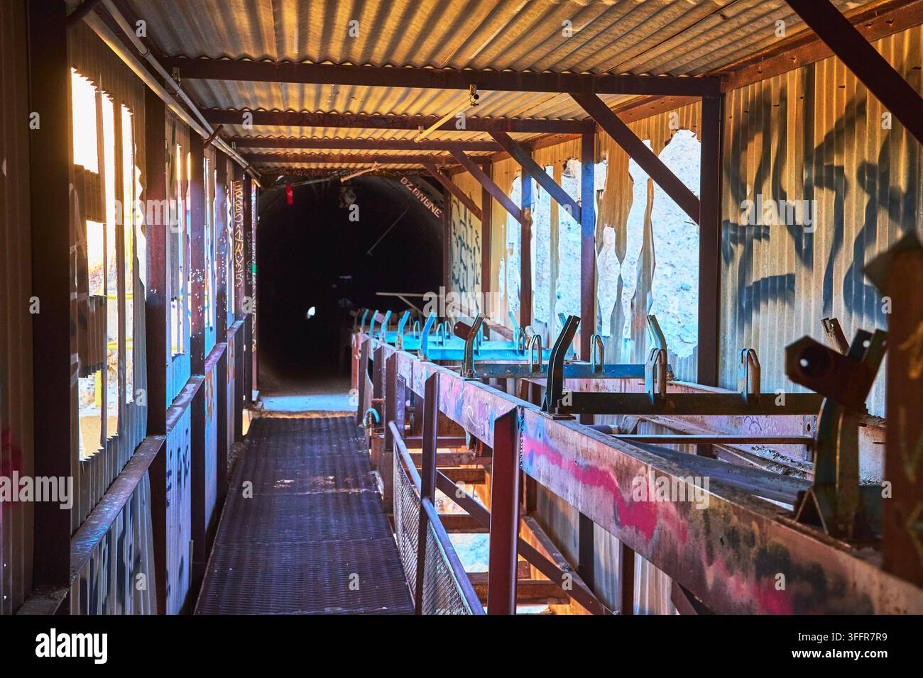 Passerelle arrugginite e muri coperti di graffiti delimitano l'interno della abbandonata mulino Goldome nella regione del Mojave in California. La luce del sole filtra attraverso Foto Stock
