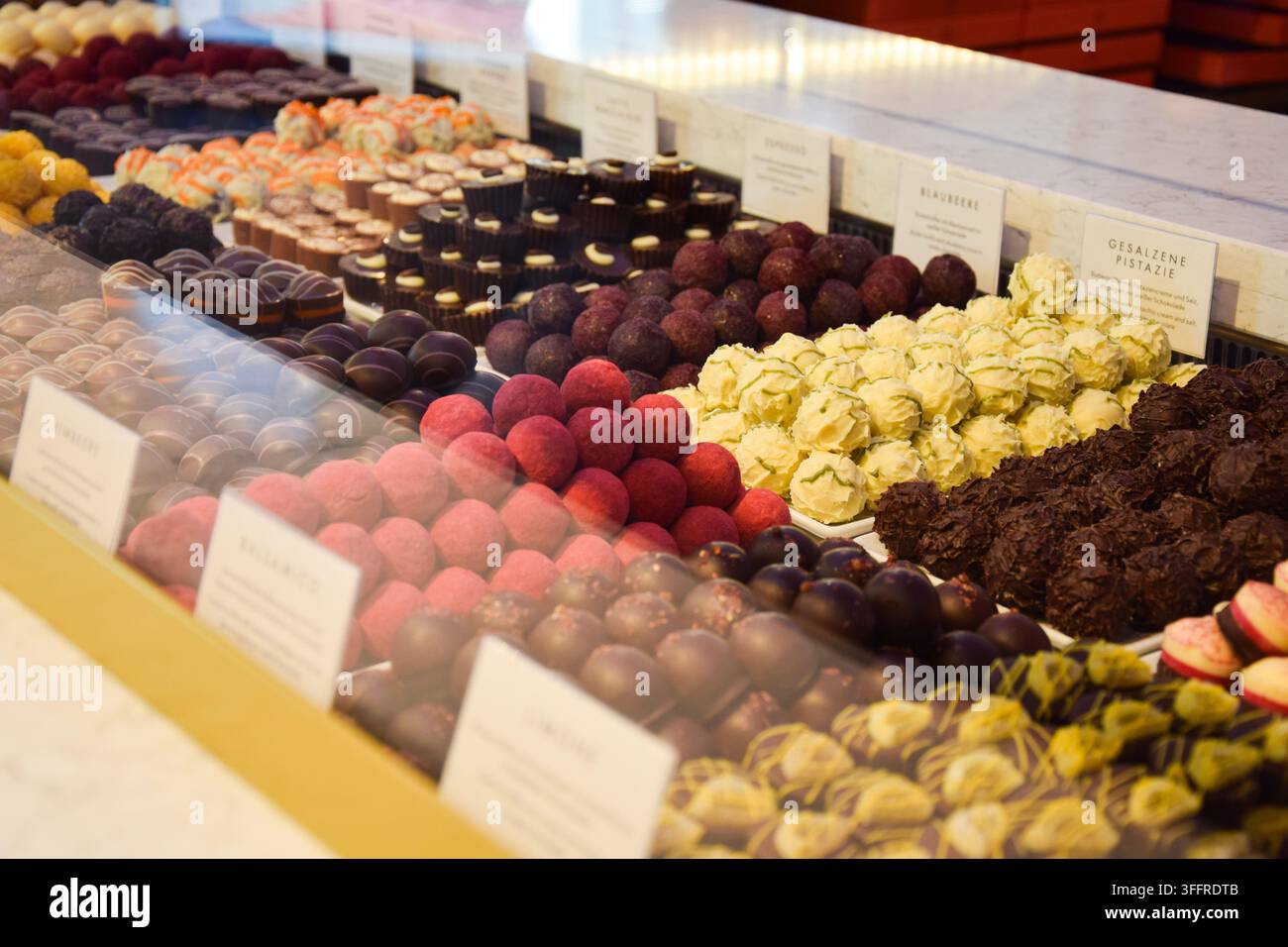 Praline di cioccolato colorate assortite in una vetrina di confetteria a Berlino, Germania Foto Stock