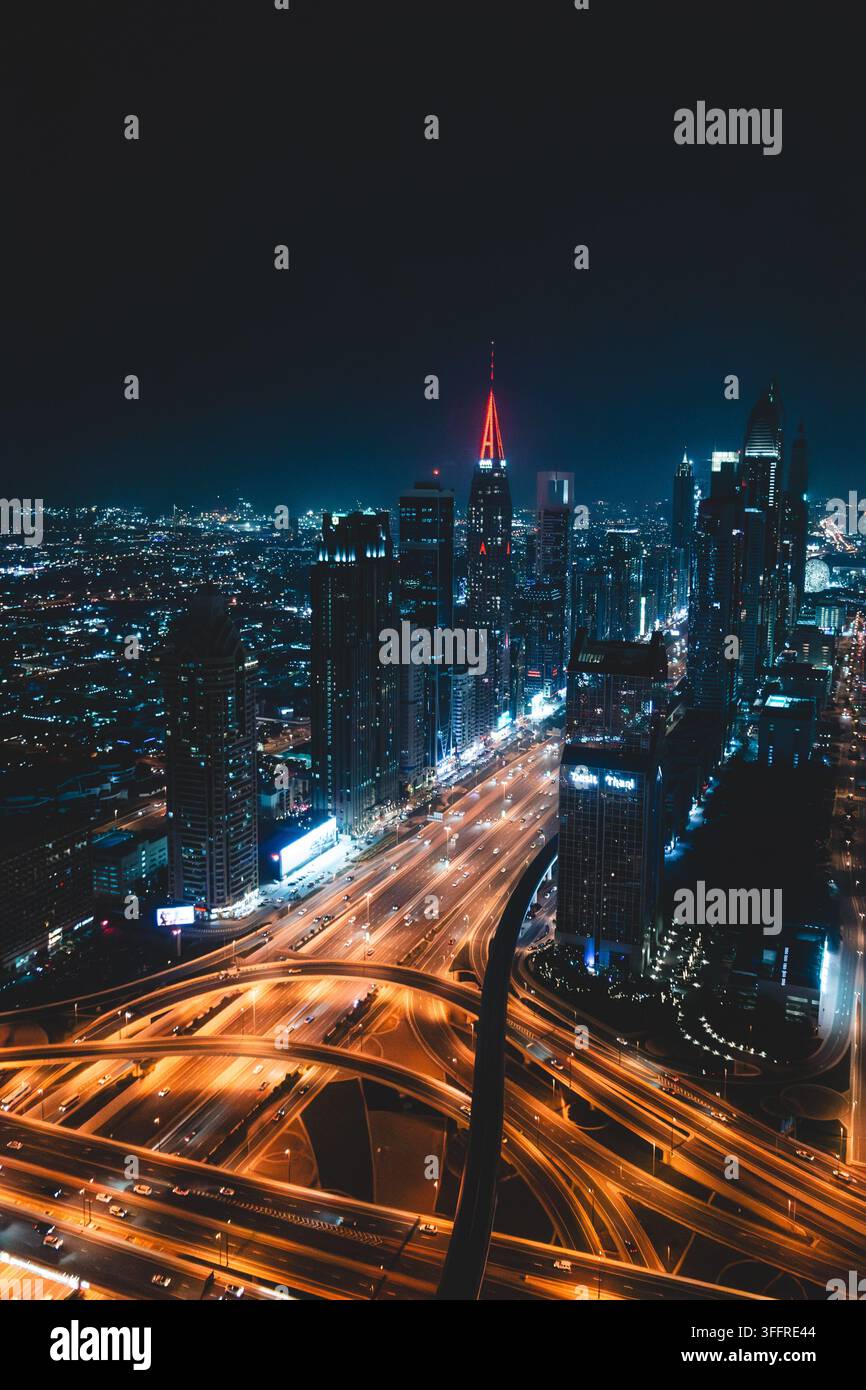 Vista notturna di Sheikh Zayed Road e del suo interscambio autostradale illuminato a Dubai, Emirati Arabi Uniti, con il distintivo A-Tower Foto Stock