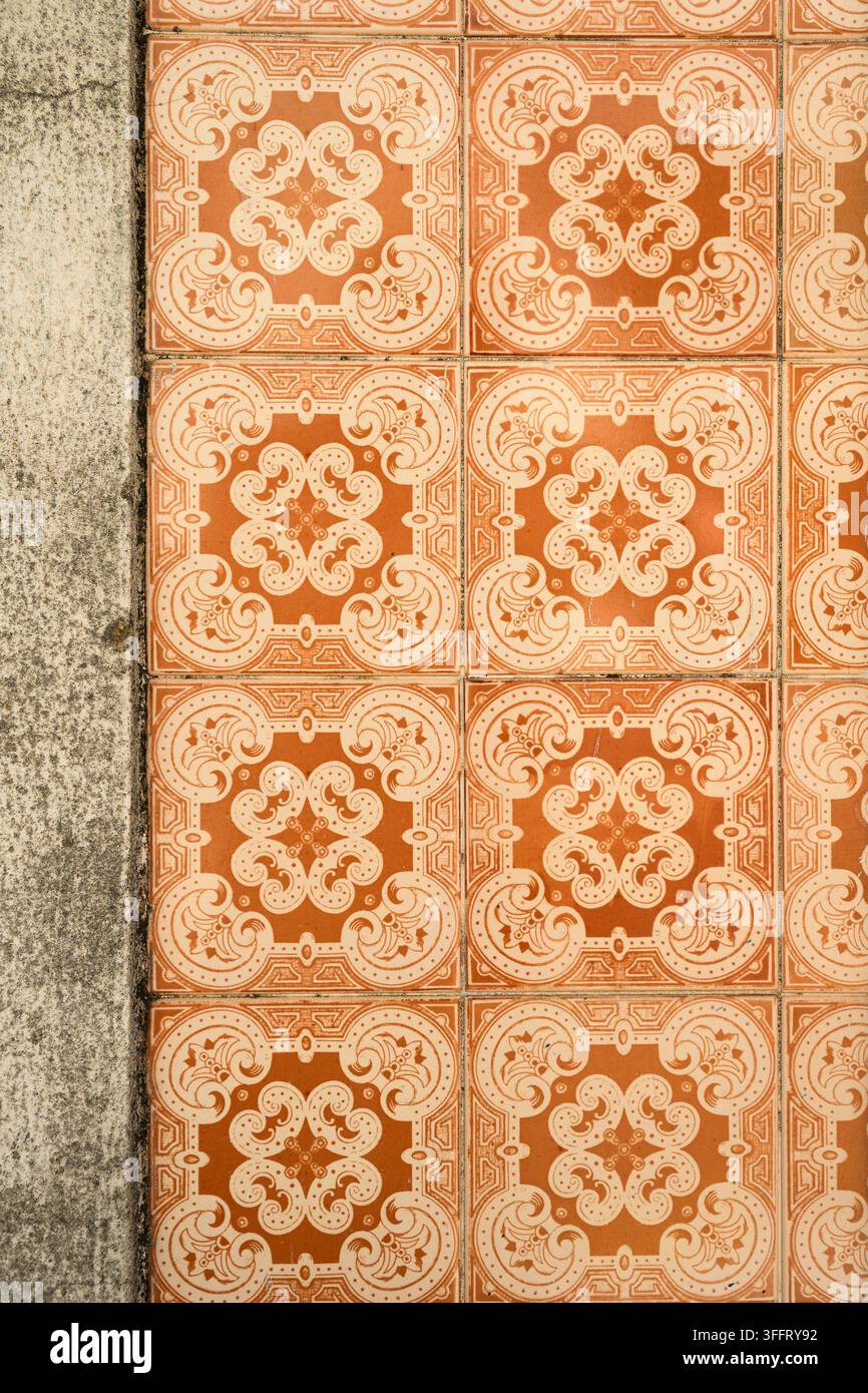 Vista ravvicinata di piastrelle decorative in ceramica arancioni con un motivo floreale ripetitivo su un muro a Lisbona, Portogallo. Foto Stock