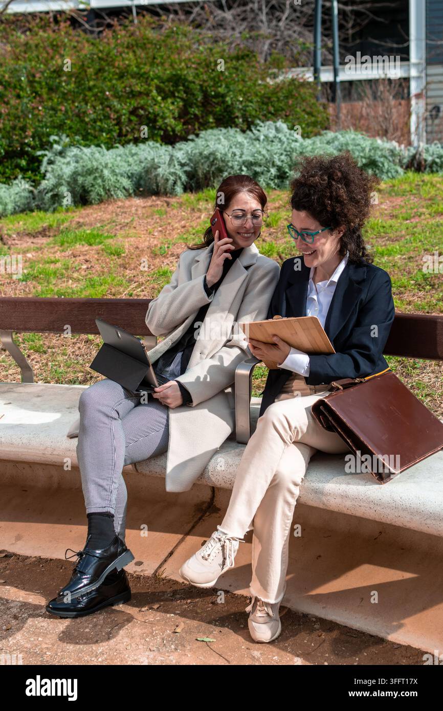 Donne d'affari che discutono di lavoro all'aperto utilizzando dispositivi digitali Foto Stock