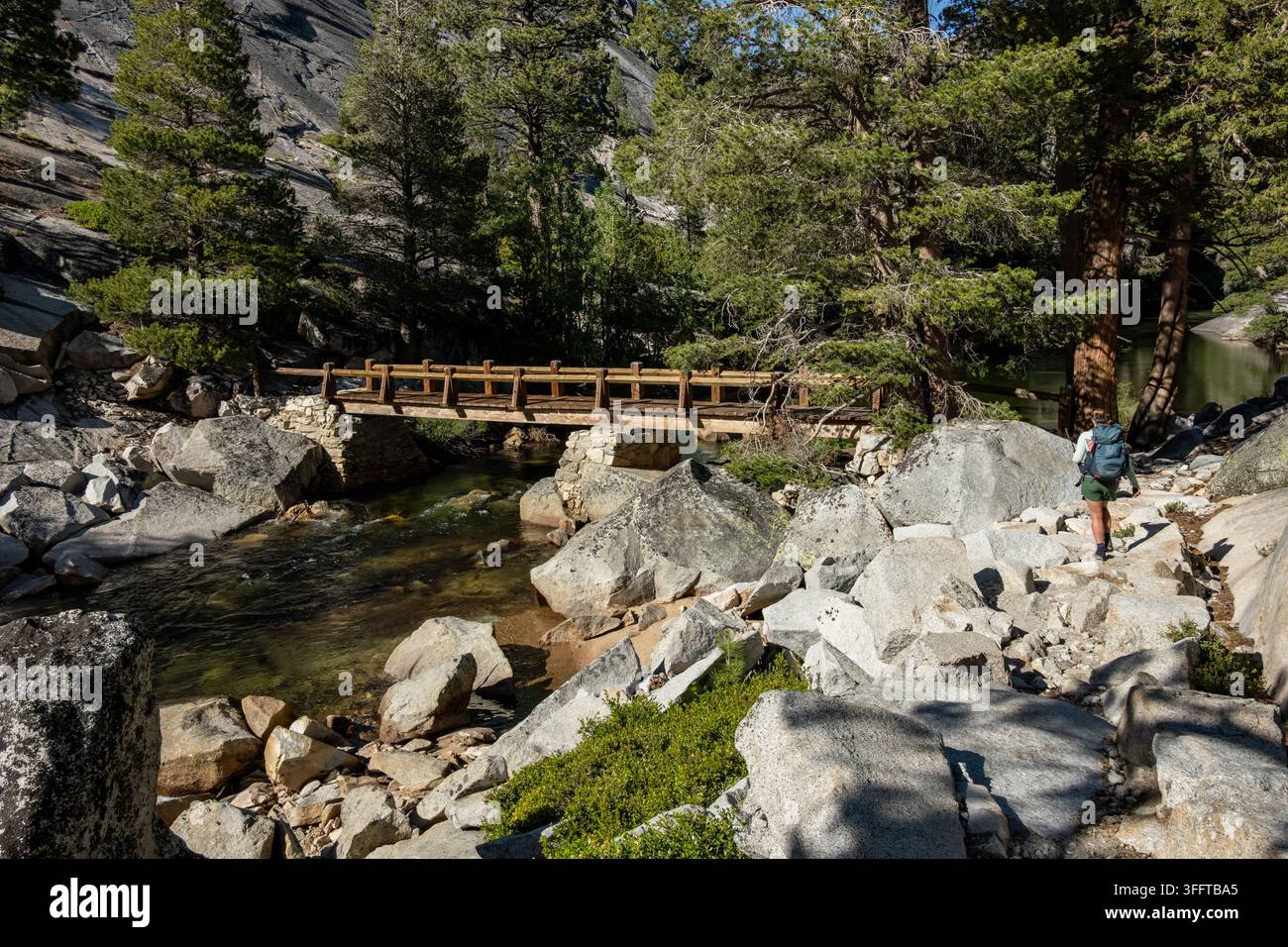 Escursionista si avvicina a un ponte sul fiume Merced nella Valle Perduta del Parco Nazionale di Yosemite Foto Stock