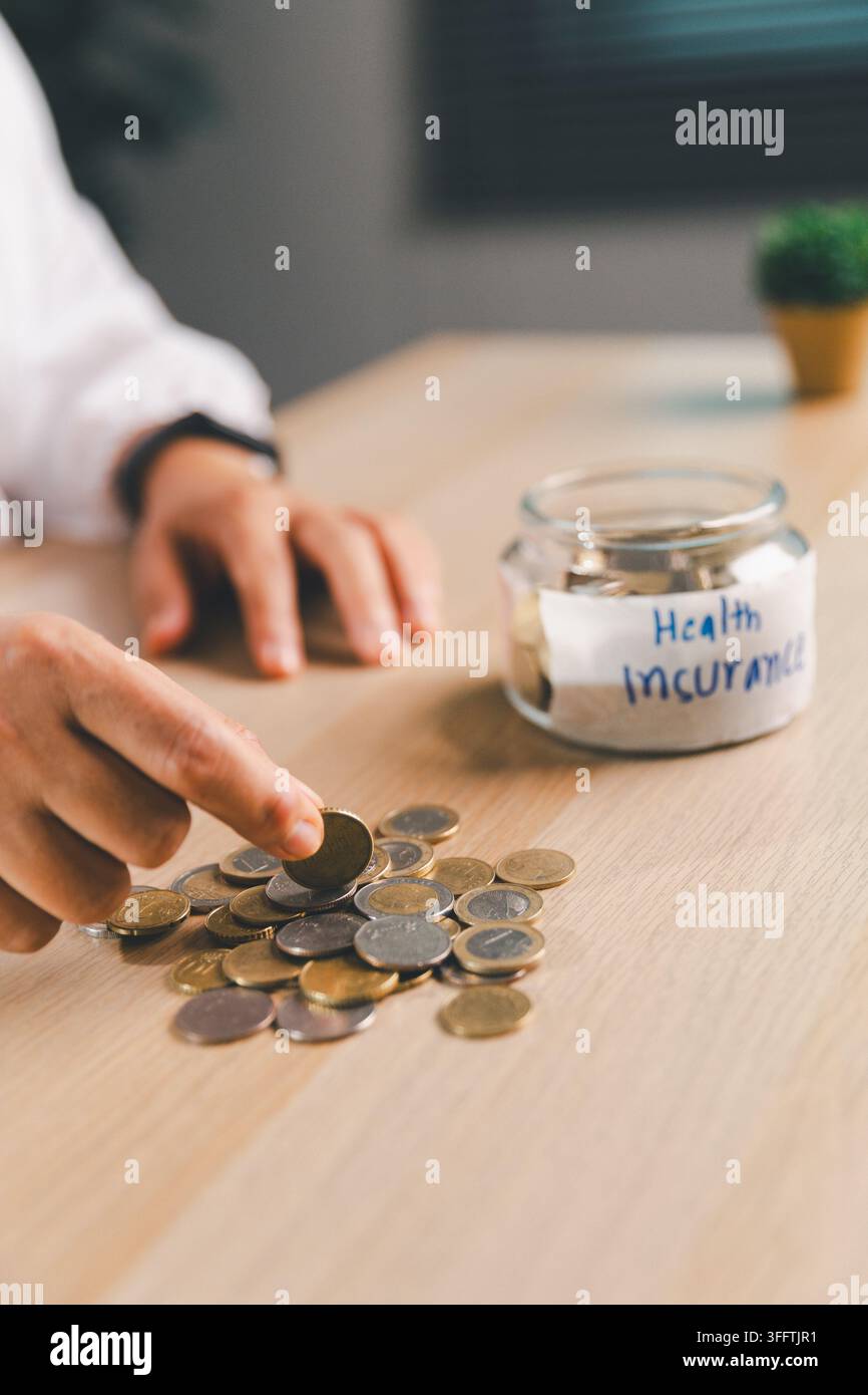 Professionista sanitario che inserisce una moneta in un barattolo etichettato Assicurazione Sanitaria, simboleggiando risparmi medici, premi assicurativi, budgeting sanitario, fin Foto Stock