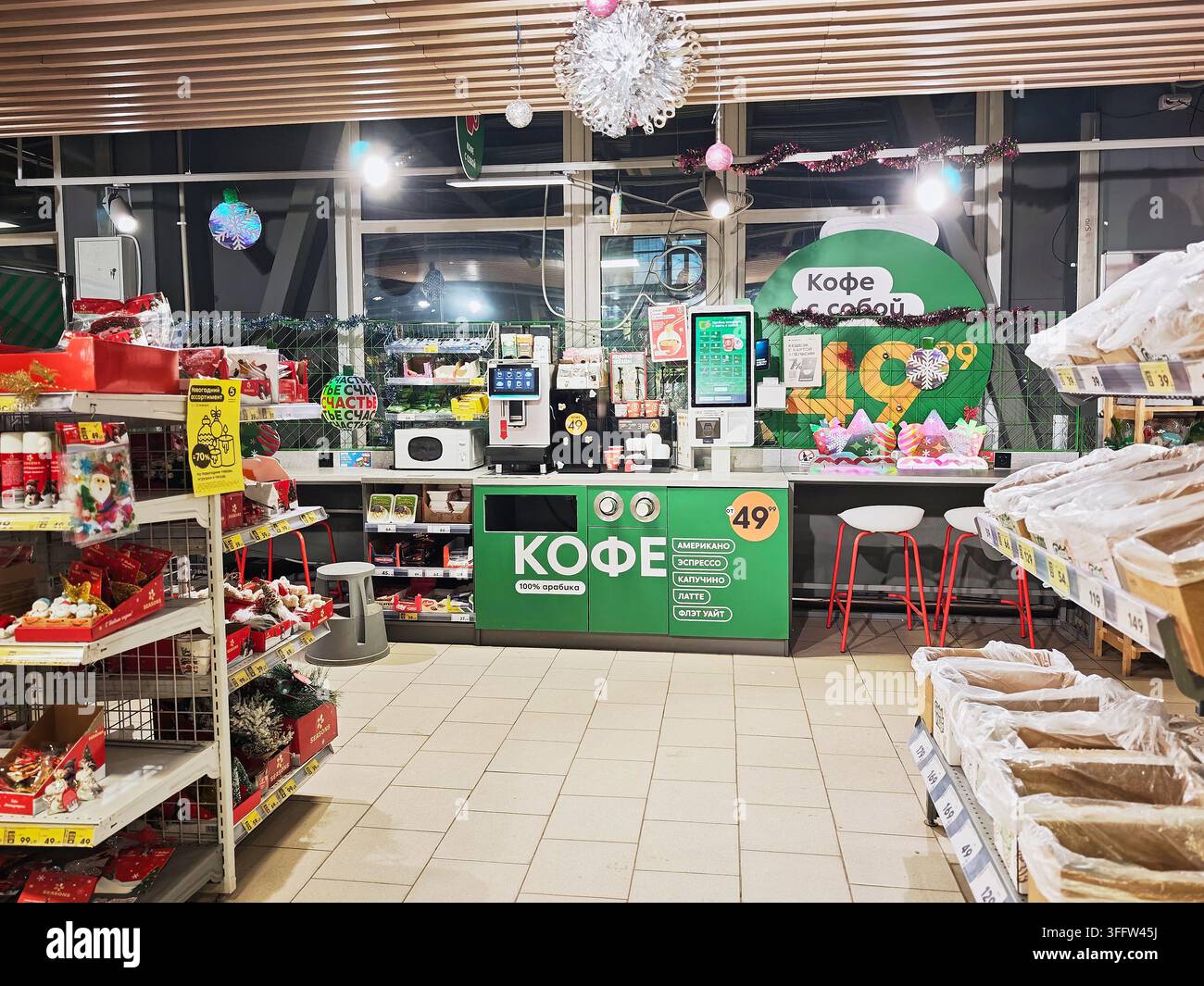 Kirov, Russia - 14 gennaio 2026: I clienti sfogliano i prodotti alimentari lungo gli scaffali di un supermercato con un banco caffè. Vari prodotti sono in esposizione Foto Stock