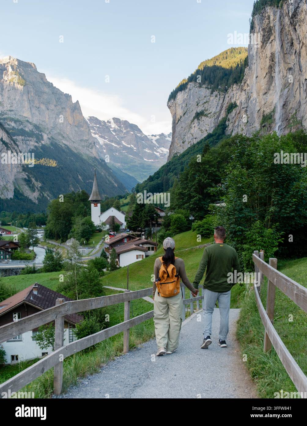 Una coppia si gode una passeggiata serena insieme lungo un sentiero panoramico a Lauterbrunnen, in Svizzera, circondata da montagne maestose e villaggi incantevoli. Il Foto Stock