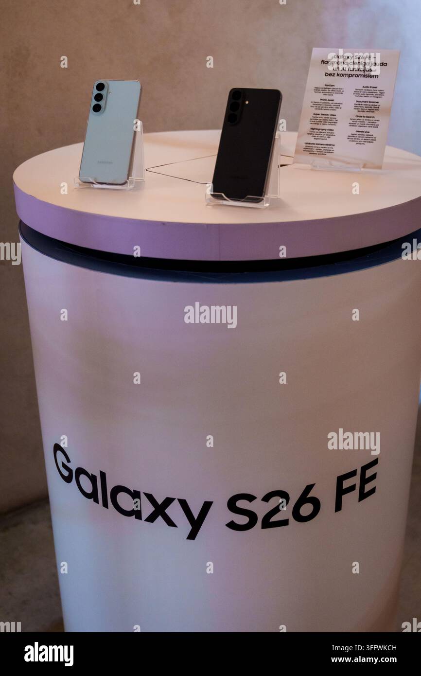 RIGA, LETTONIA. 25 agosto 2026. Colonna di presentazione del prodotto a un evento di lancio con il titolo del marchio Galaxy S26 FE e due varianti di colore del nuovo sma Foto Stock