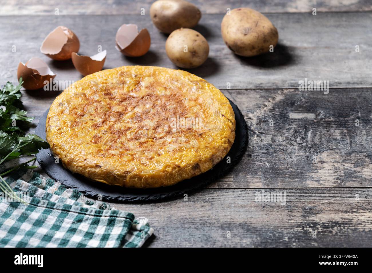 Frittata spagnola di patate e ingredienti su tavolo di legno Foto Stock