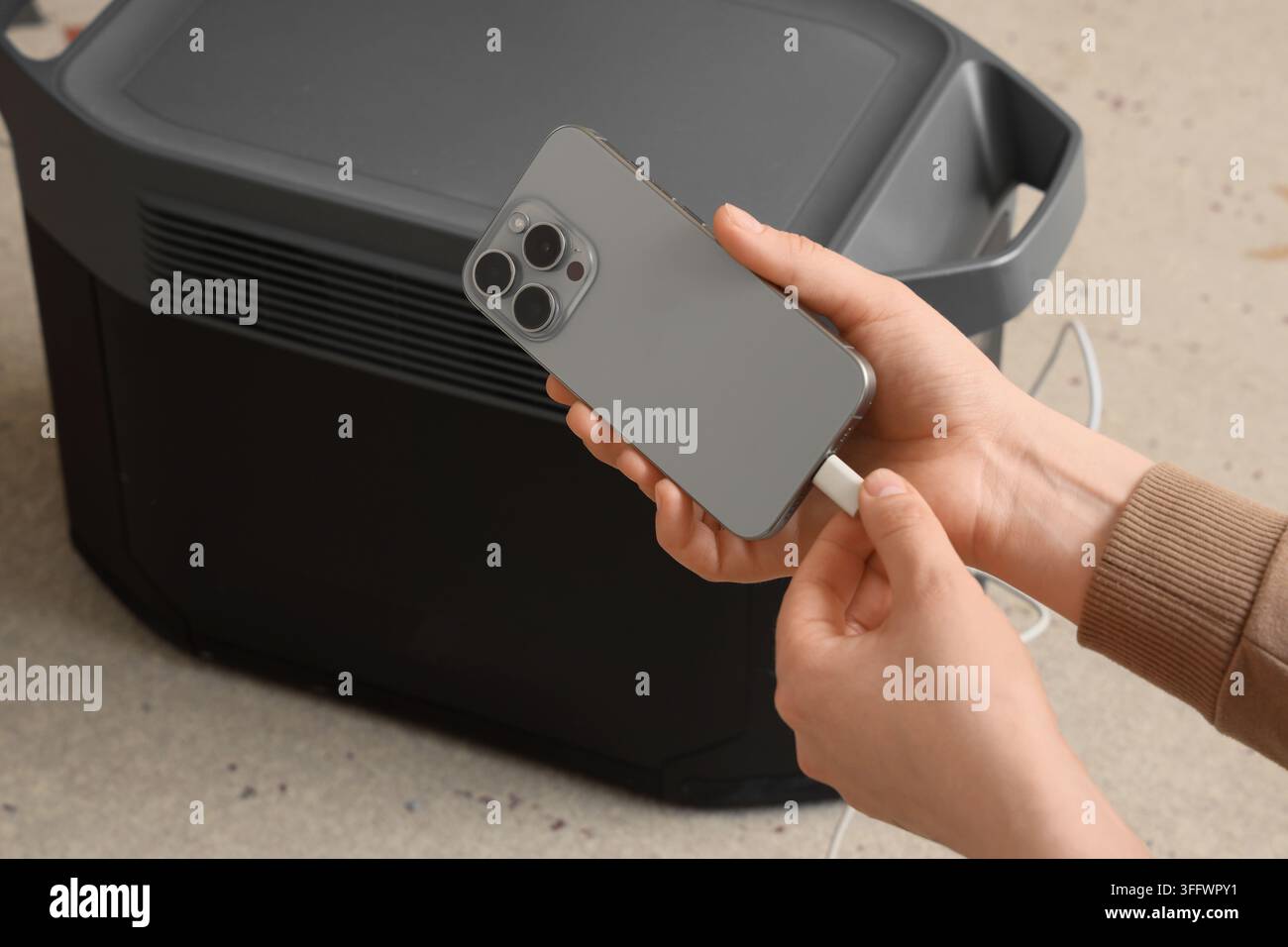 Indipendenza energetica e alimentazione portatile, persona che ricarica lo smartphone con una stazione a batteria ad alta capacità per vivere fuori dalla rete e come backup di emergenza Foto Stock