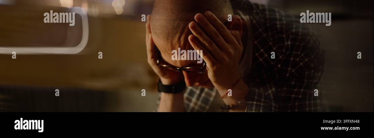 Uomo stressato che si tiene la testa e soffre di esaurimento e stanchezza Foto Stock