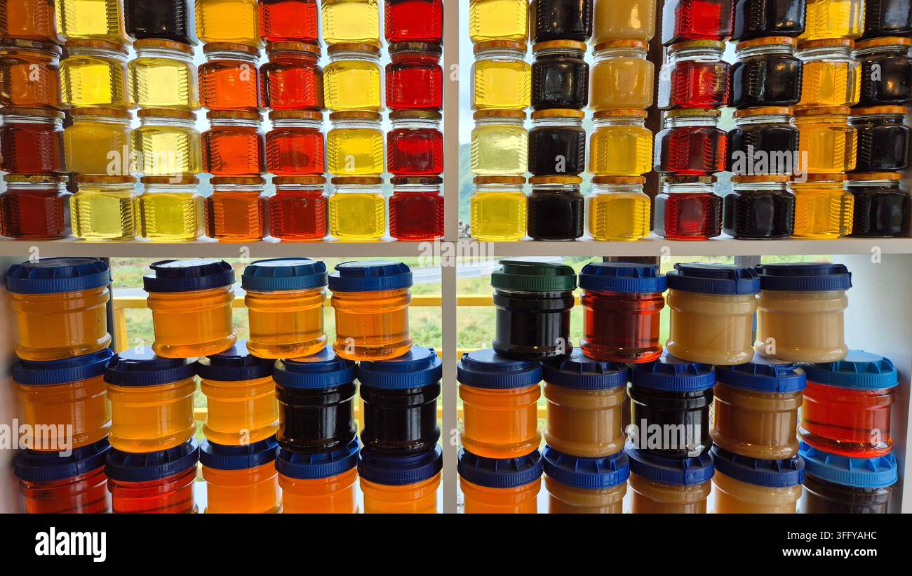 Barattoli di miele naturale biologico puro in varie tonalità ambrate dorate in mostra in un mercato di un villaggio georgiano - Immagine stock catturata con smartphone