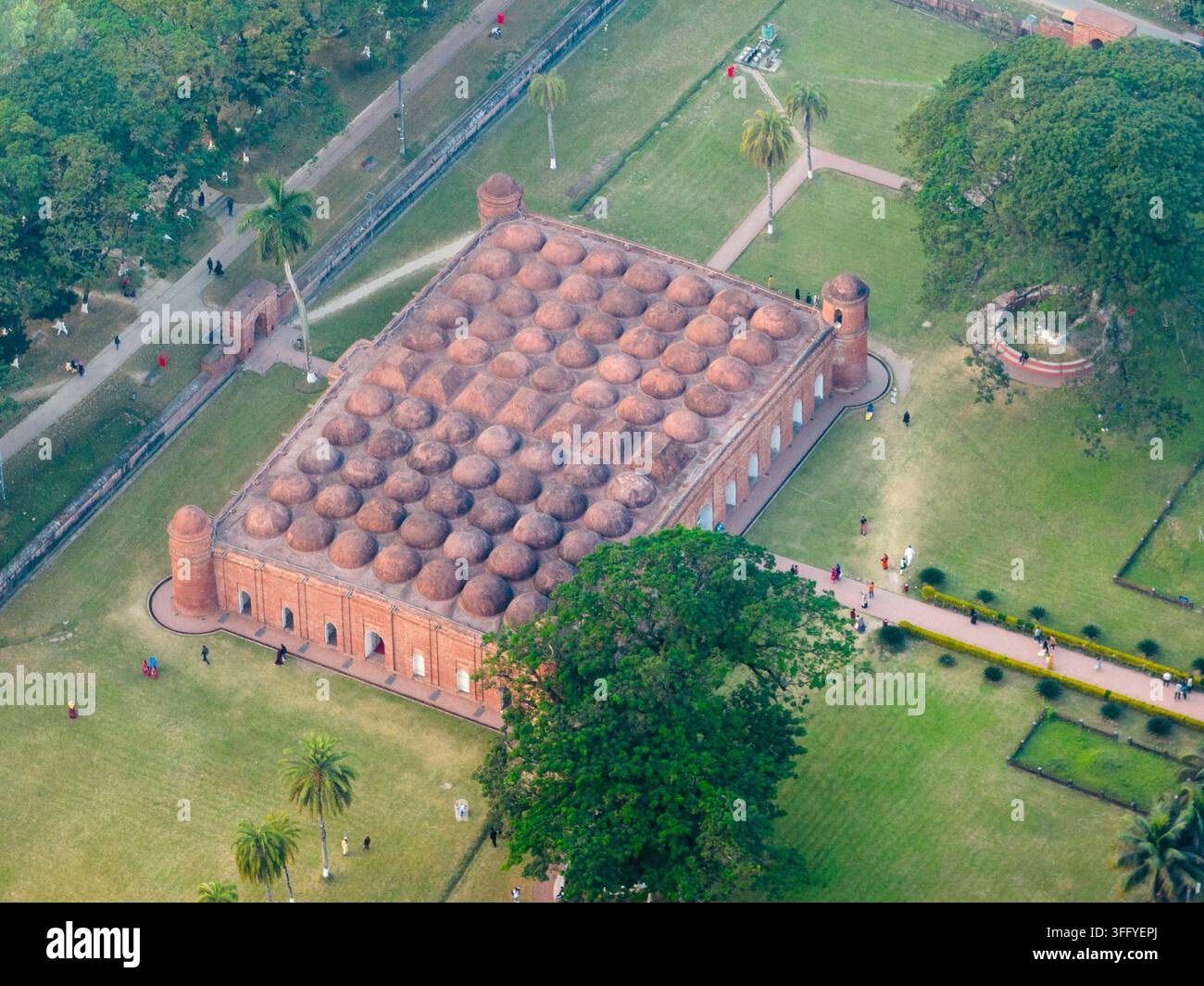 Vista aerea della storica moschea Sixty Dome con i suoi distintivi cupole multiple, architettura in mattoni rossi, circondata da prati verdi e palme in Foto Stock