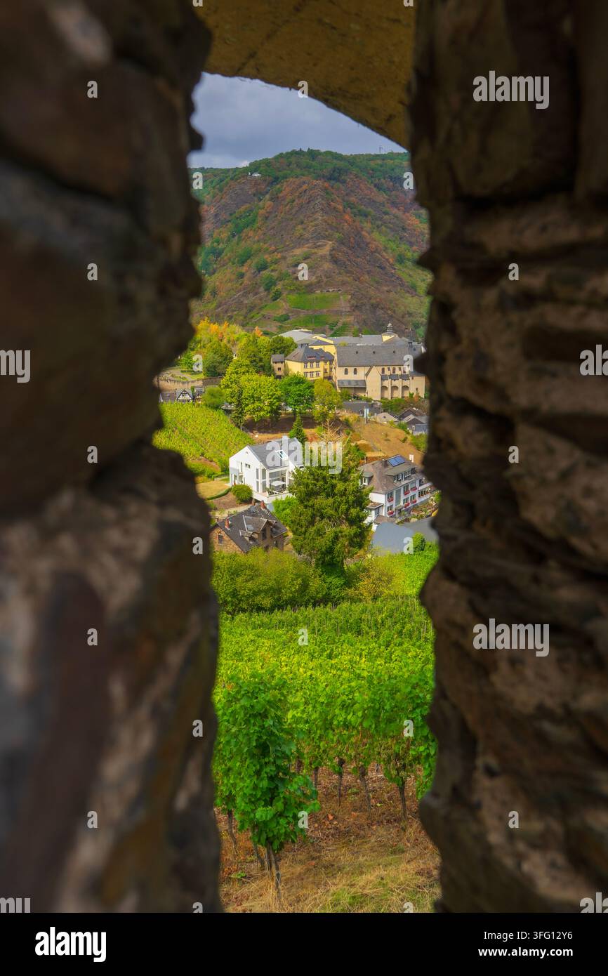 Cochem, Germania – 28 febbraio 2026: Vista della valle della Mosella, vigneti e colline boscose attraverso un'apertura in pietra del Reichsburg Cochem. Foto Stock