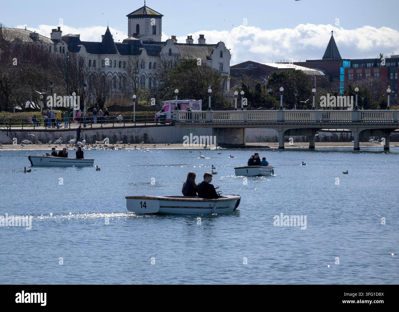 Visitatori al Southport Marine Lake, che noleggiano affascinanti barche a remi in legno. Southport, Regno Unito. Foto Stock
