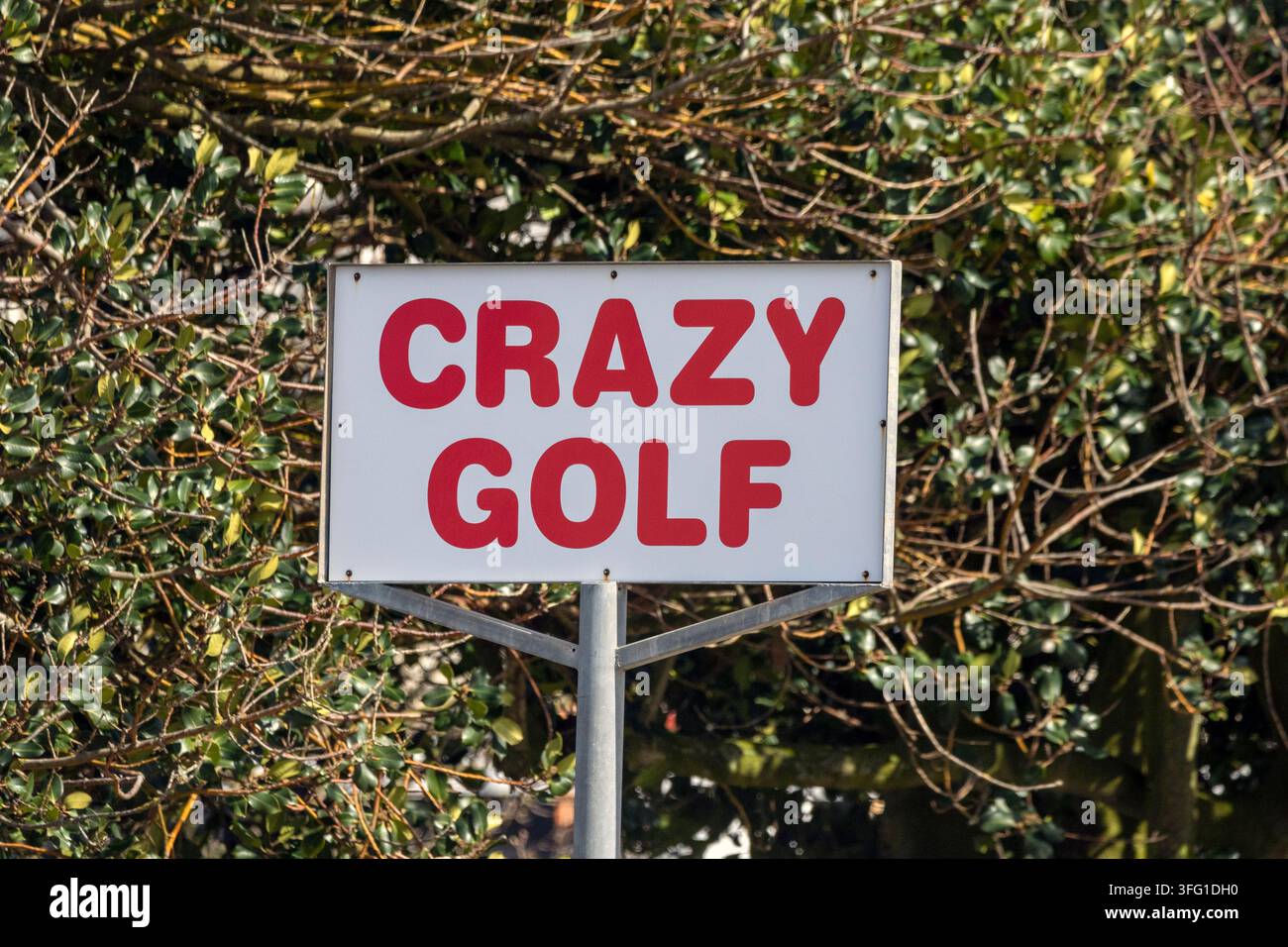 Un cartello rettangolare bianco con lettere rosse in grassetto che recita "CRAZY GOLF", montato su un palo di metallo. Southport, UK. Foto Stock