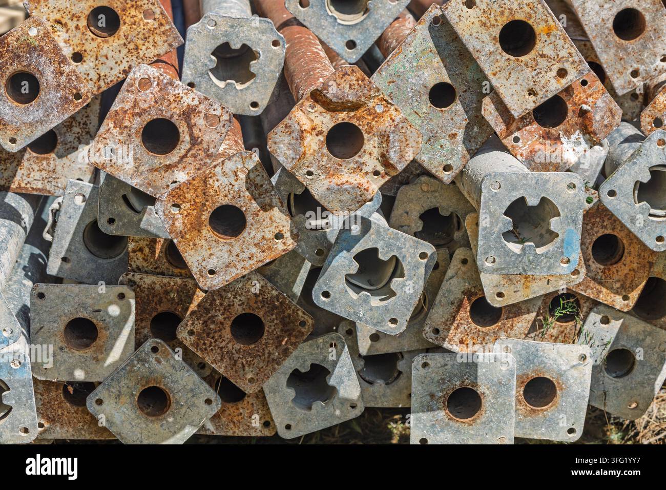 Vista ravvicinata di piastre di base di impalcature arrugginite impilate che mostrano metallo stagionato, corrosione sfogliata e fori geometrici ripetitivi. Adatto per l'industria Foto Stock