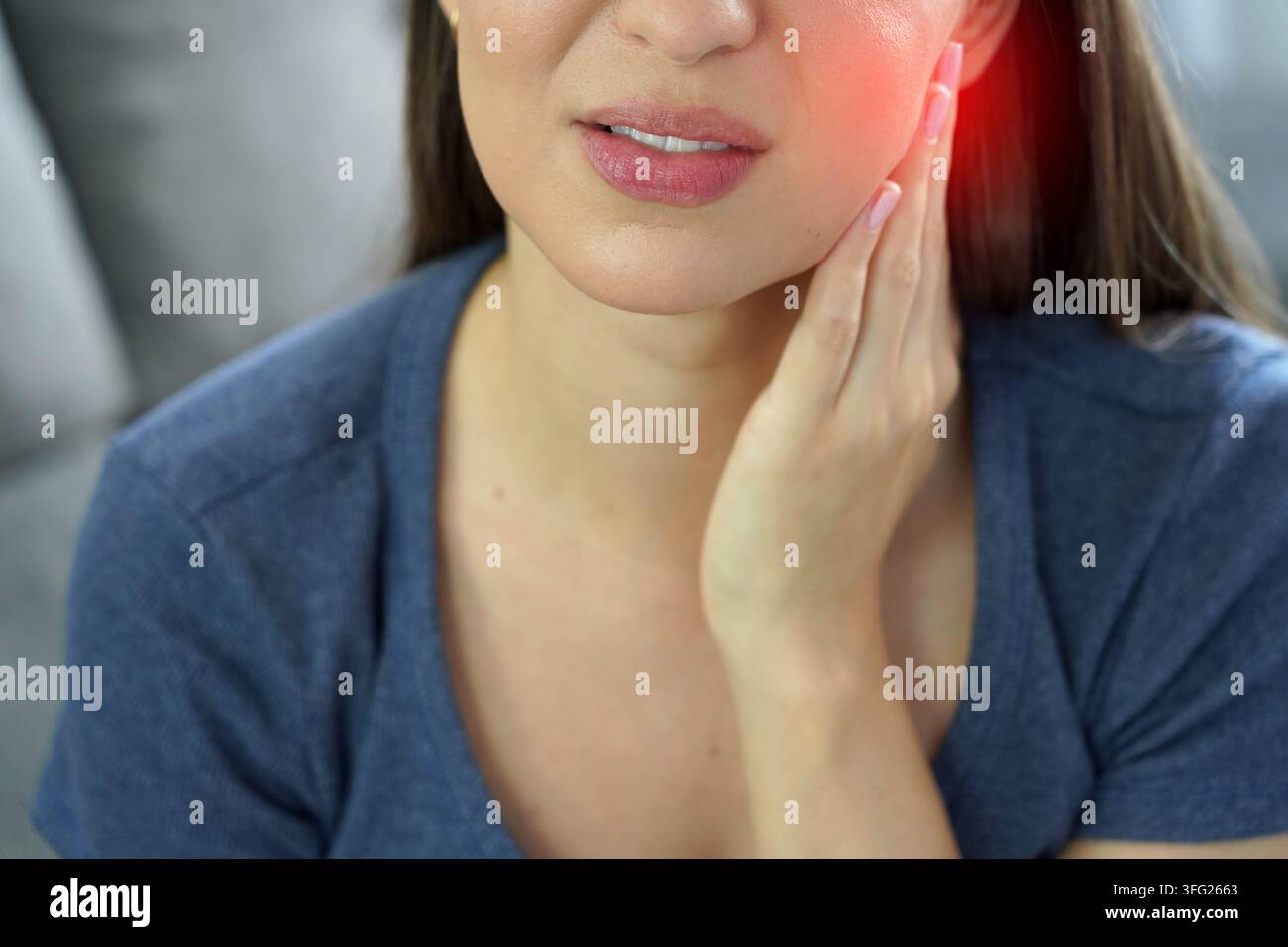 Giovane donna che tocca la mascella e digrigna i denti per il forte dolore dovuto al disagio dei denti del giudizio Foto Stock