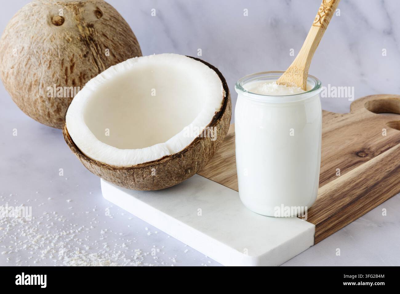 Noce di cocco e yogurt al cocco, intere e tagliate a metà, con polpa fresca Foto Stock