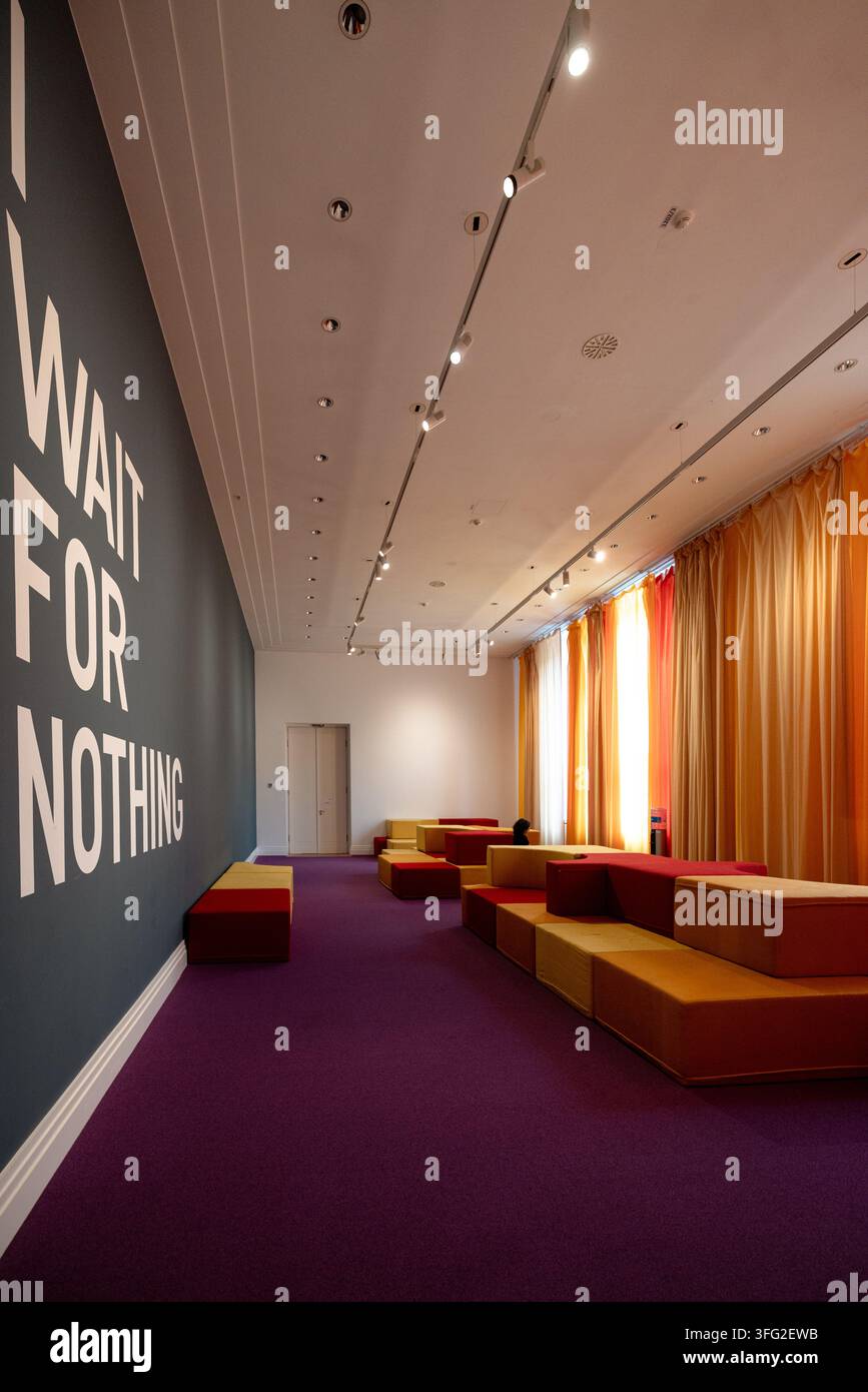 La sala d'attesa senza titolo del 2025 di Rirkrit Tiravanija al Gropius Bau presenta la scritta murale I WAIT FOR NOTHING, moquette viola e rivestimenti colorati Foto Stock